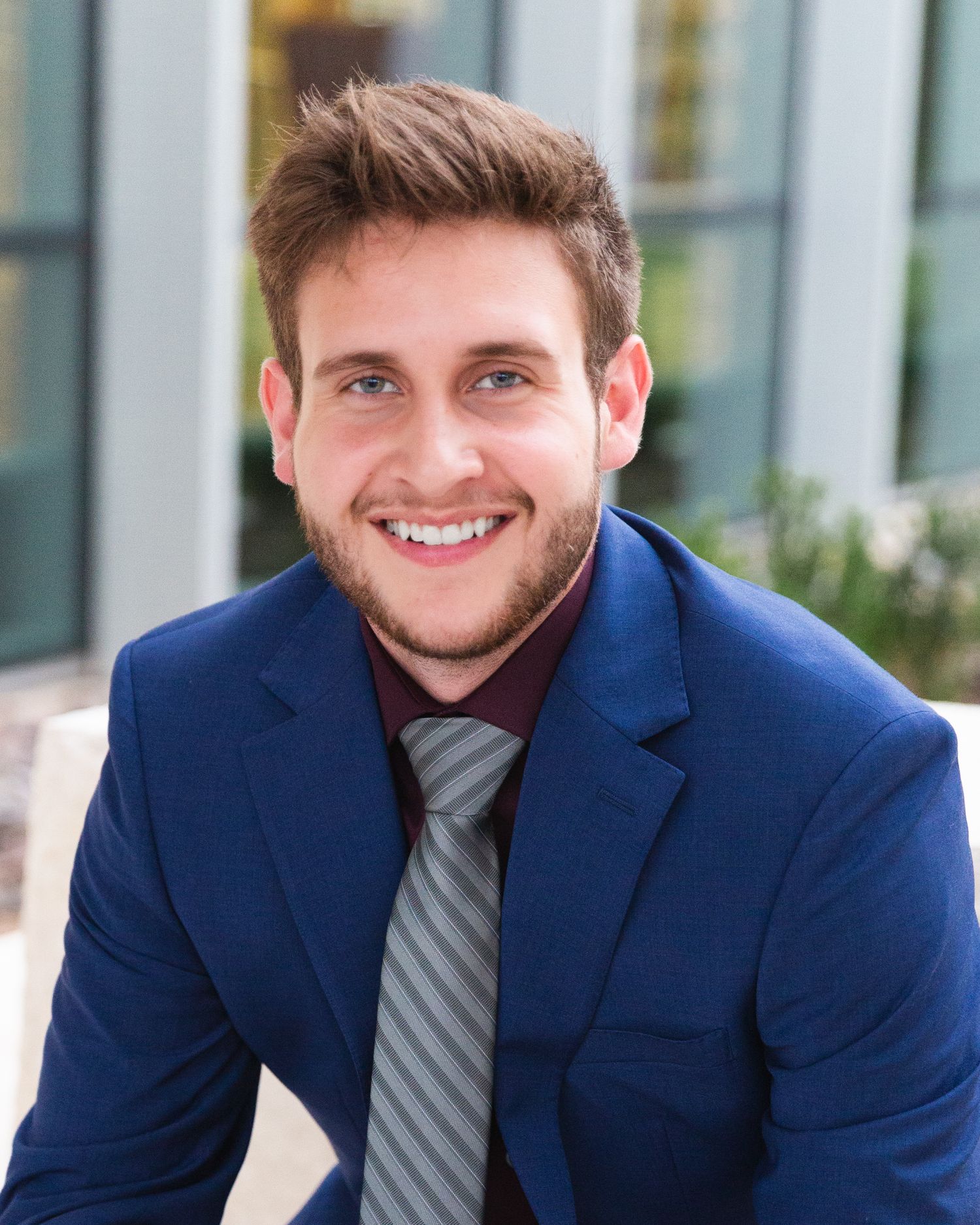 Professional portrait series showing person in navy suit and striped tie against office building.