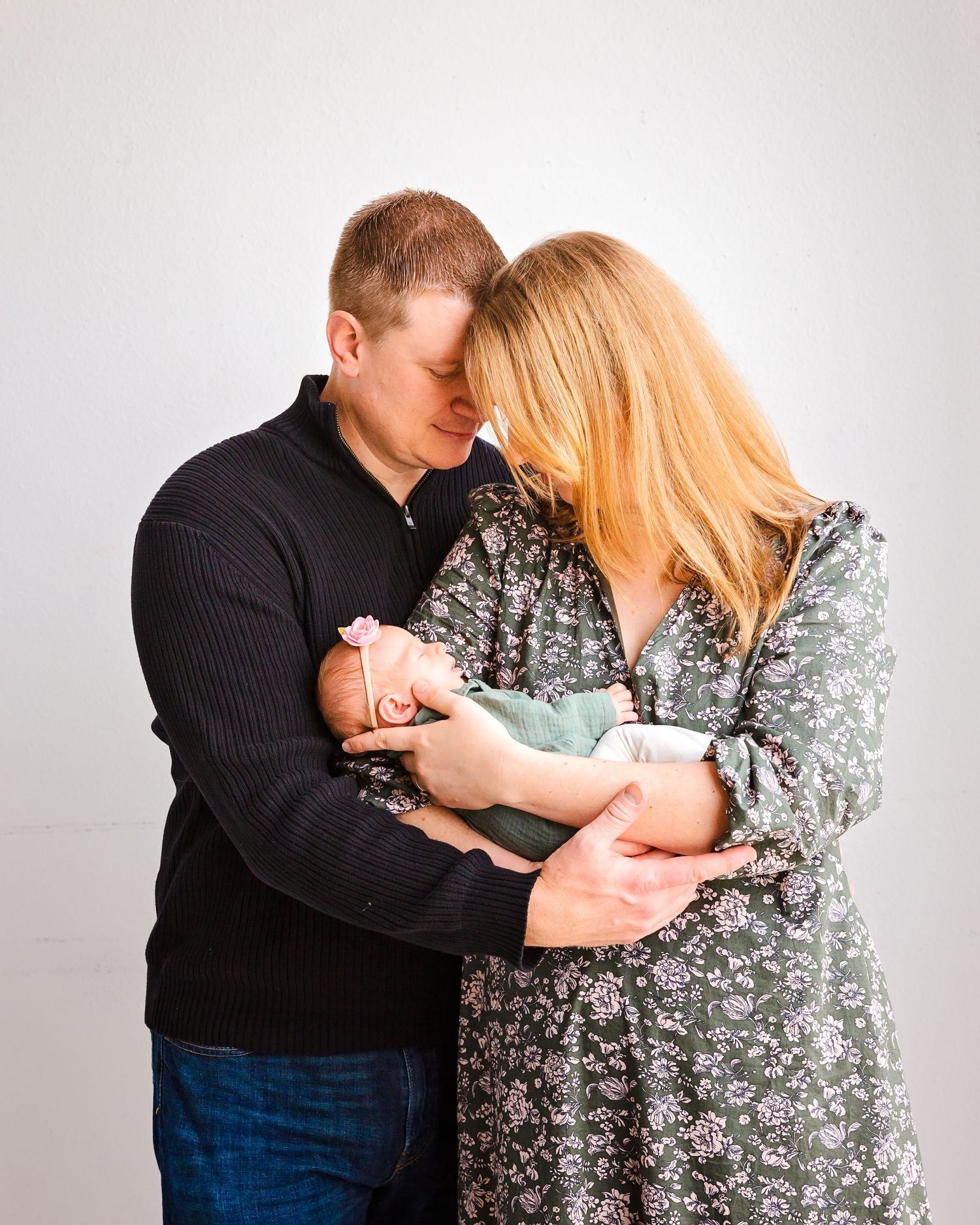 A couple embraces in a series of romantic poses against a light gray studio backdrop.