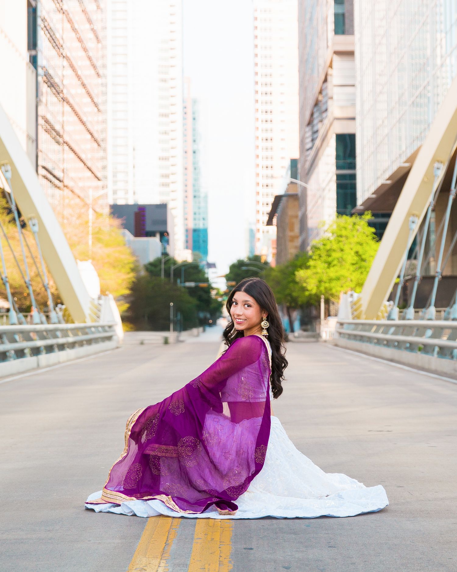 Senior portrait session in downtown Austin, TX. Butterfly Bridge, purple dress twirling on a bridge with city buildings in background.