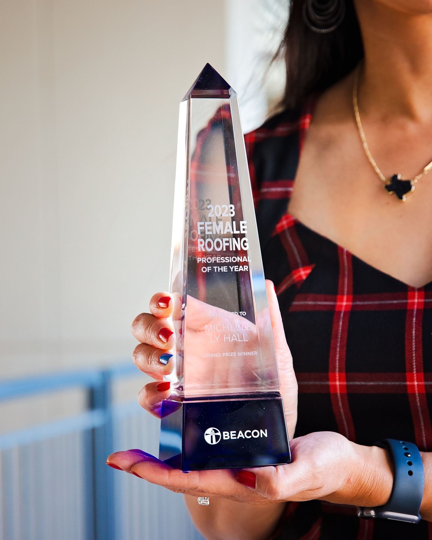 Close-up of hands holding clear crystal trophy award against light background.