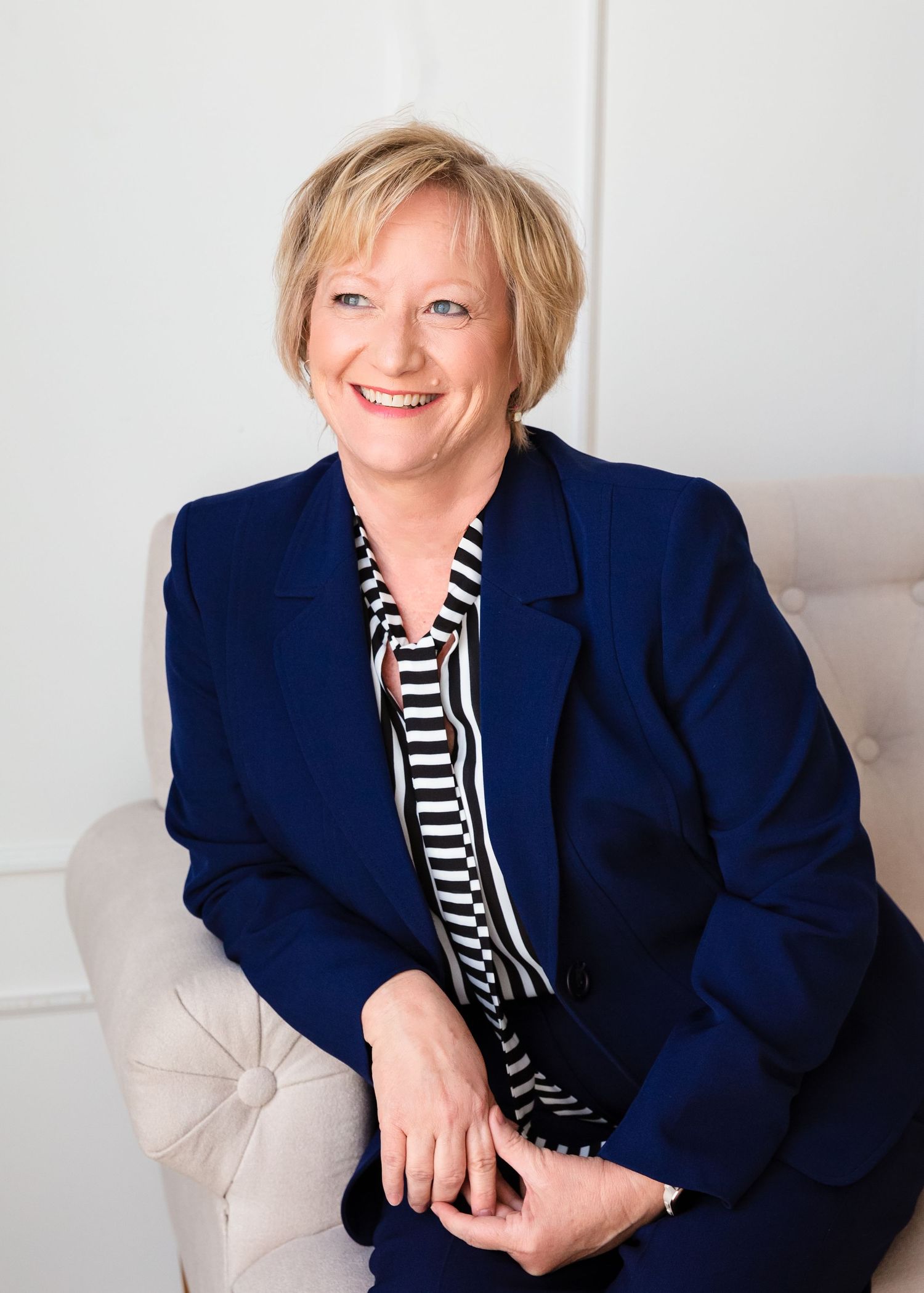 Professional headshots of person in navy blazer and striped top against white background.