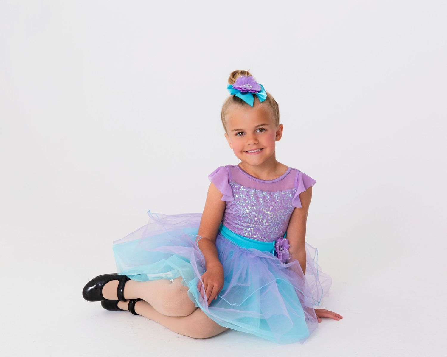 Dancer in purple and blue tulle dress strikes elegant poses against white studio background.
