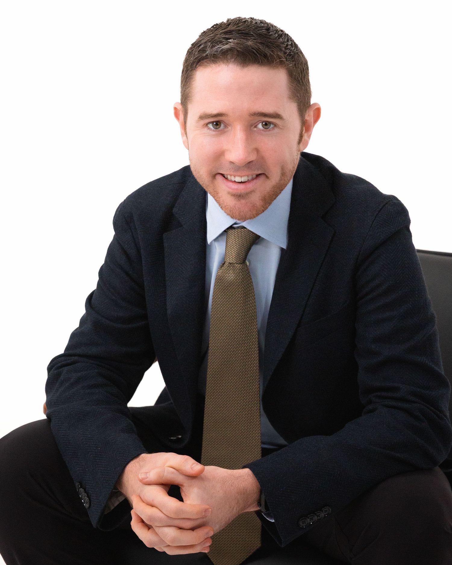 Business portrait series showing person in dark suit and brown tie against white background.