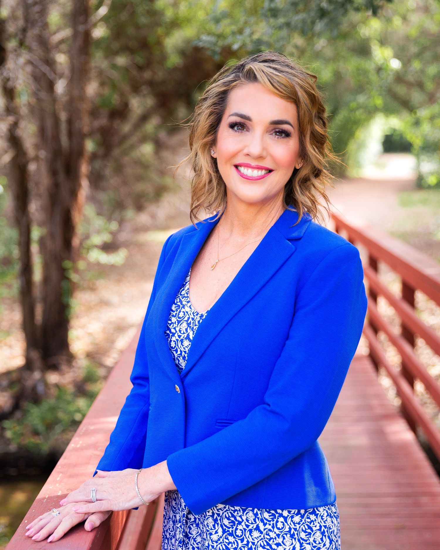Professional outdoor portraits of person in royal blue blazer on wooden bridge pathway.