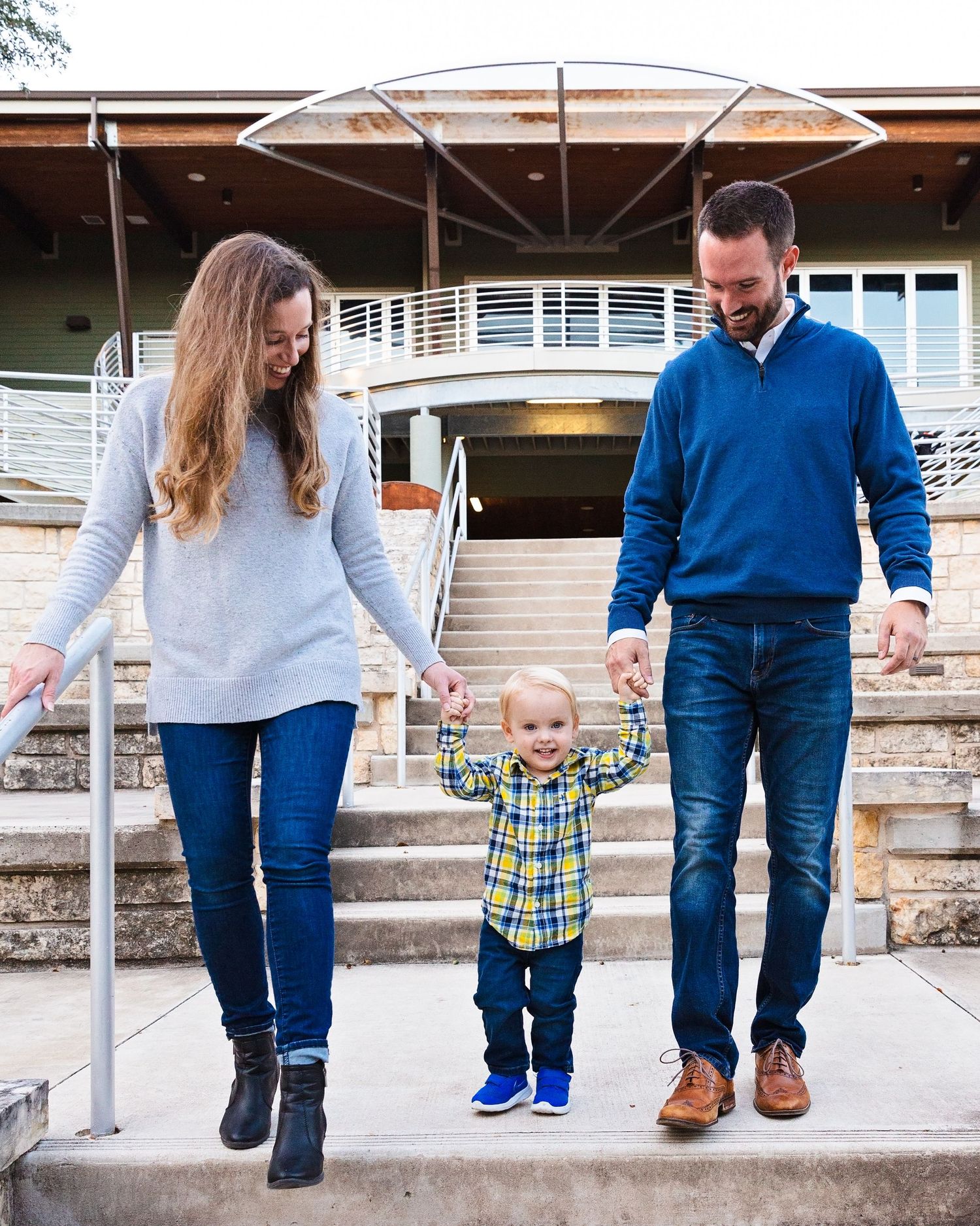 Family with toddler walking together on stone steps in coordinated blue and white outfits. Rabb House in Round Rock, TX
