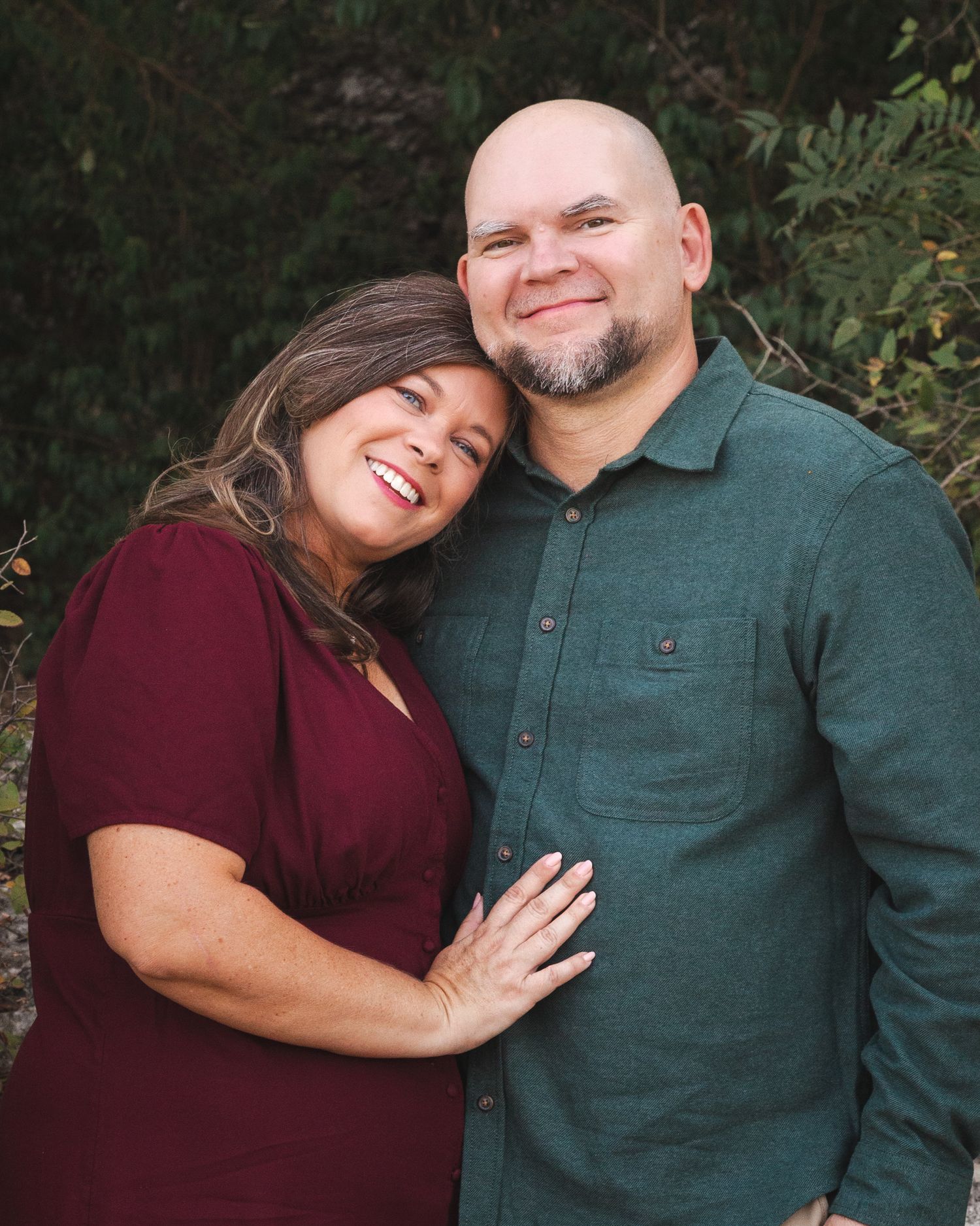 Couple in burgundy and green casual wear shares intimate moment outdoors.