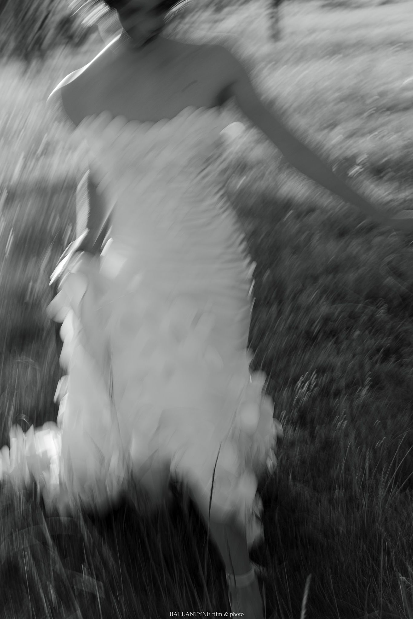 Abstract motion blur photograph of a white wedding dress in a field.