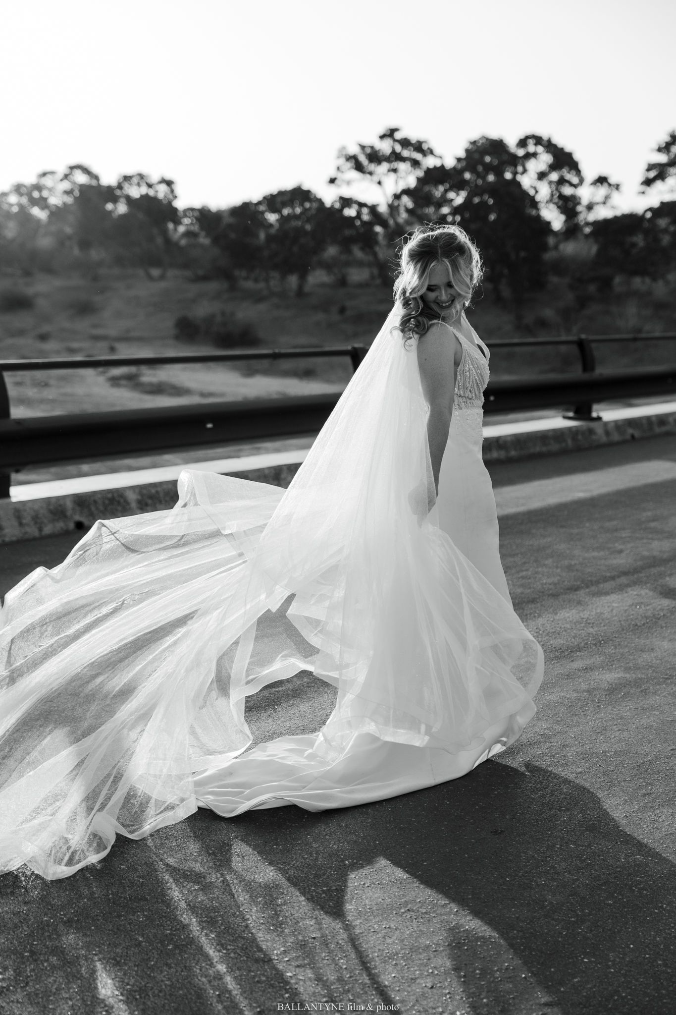 Flowing white wedding veil billowing dramatically in the wind against a dark outdoor backdrop.