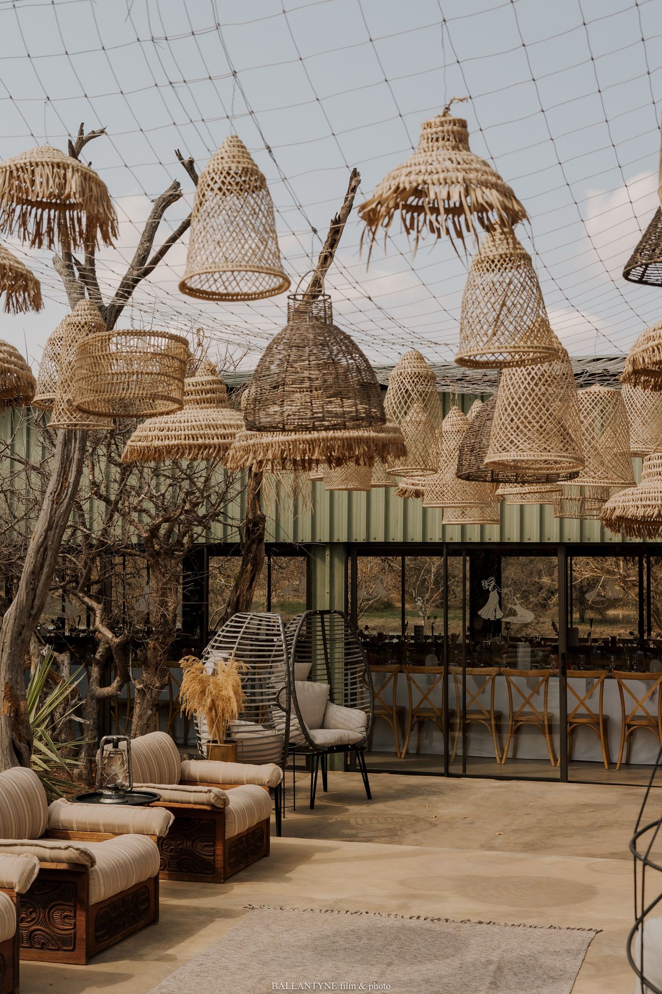 Outdoor lounge area decorated with hanging woven rattan lampshades and comfortable seating.