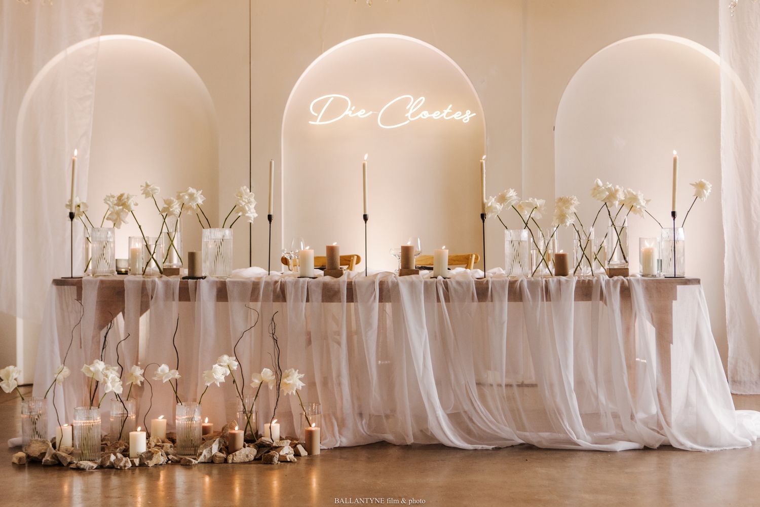 Elegant wedding reception venue with white draping, chandeliers, and romantic candlelight decor.