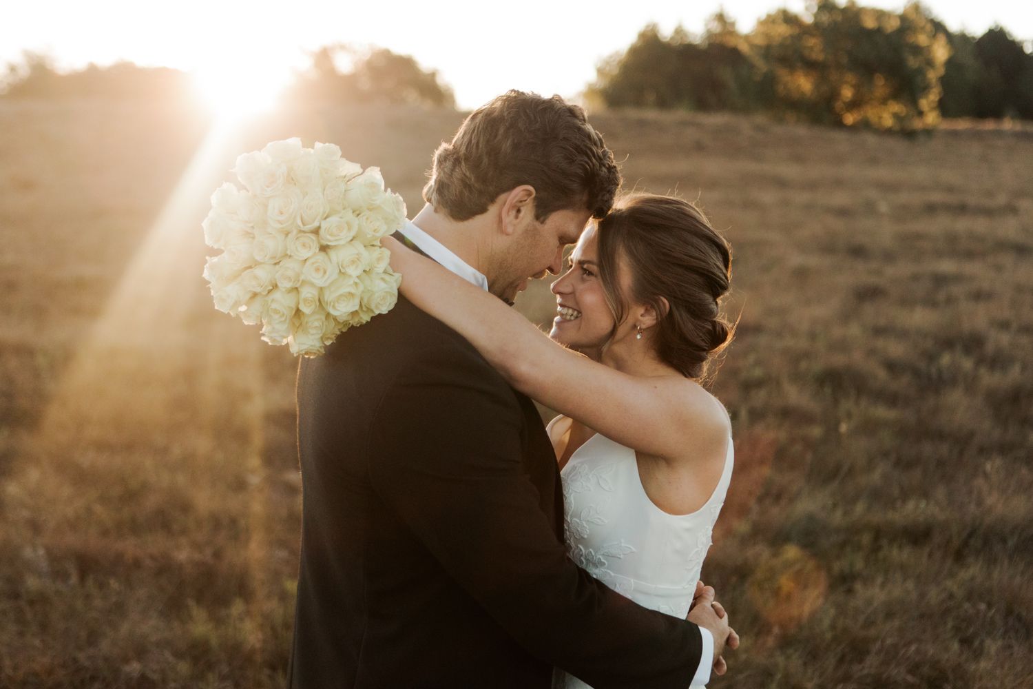 Romantic sunset wedding portrait with white bouquet.