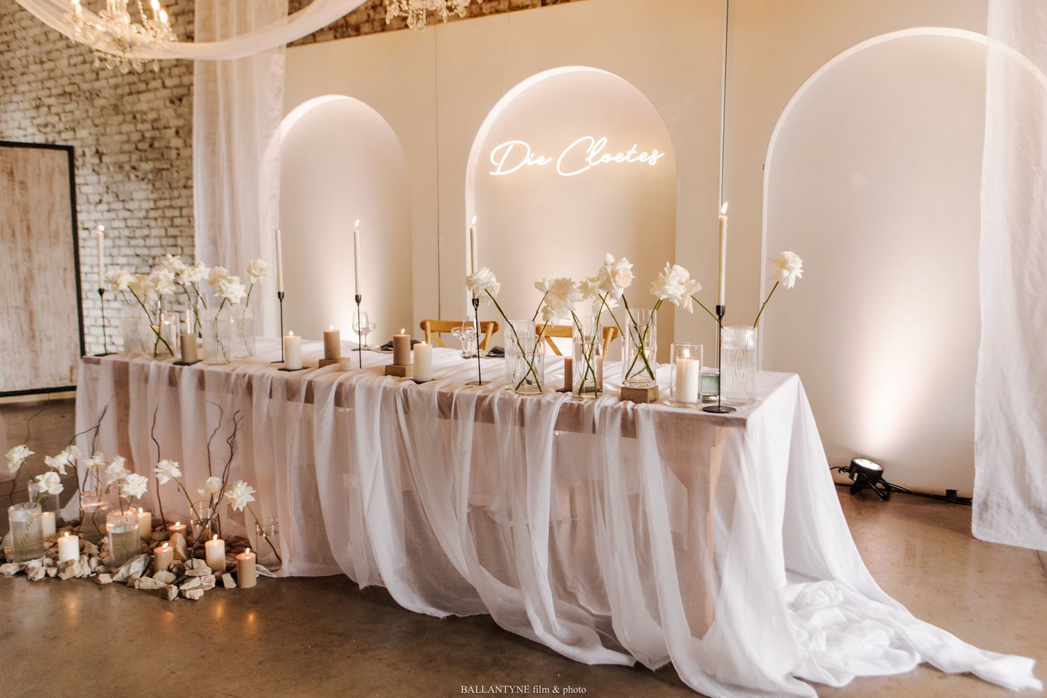 Modern wedding reception venue with white draping and elegant lighting design.
