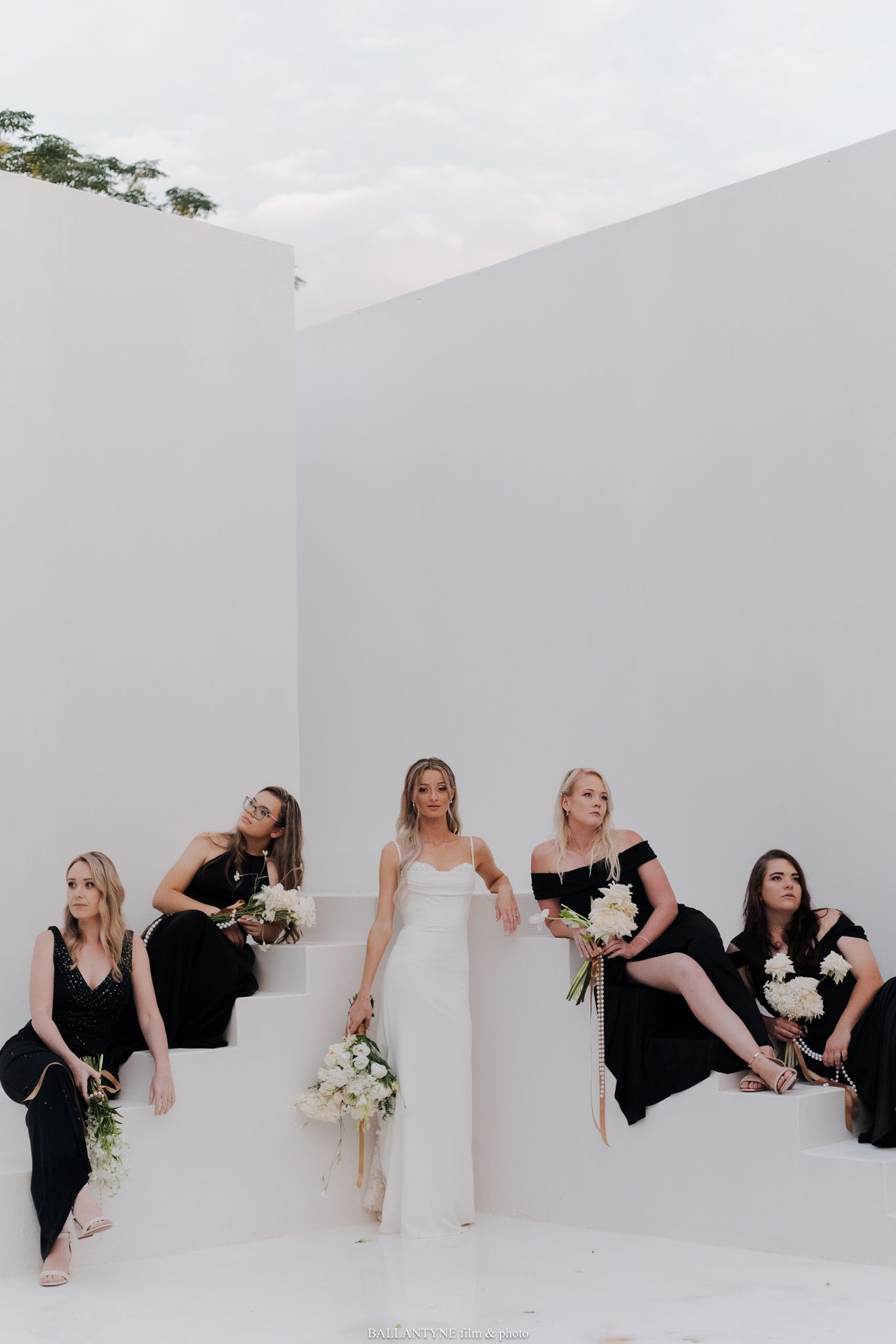 Creative wedding party photo showing bridesmaids peeking through a white wall.