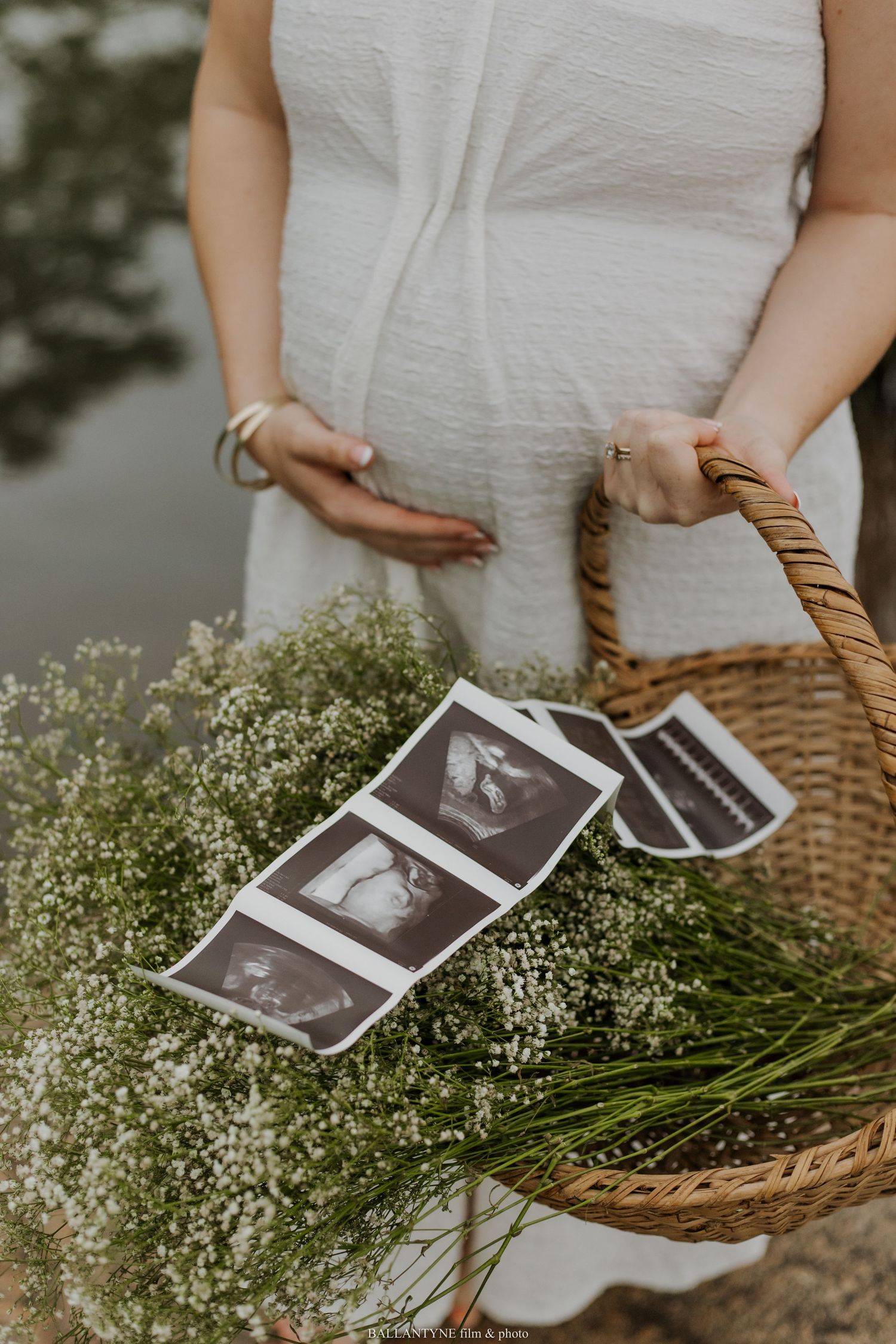 A basket of baby's breath flowers with ultrasound photos displayed in a maternity announcement setting.