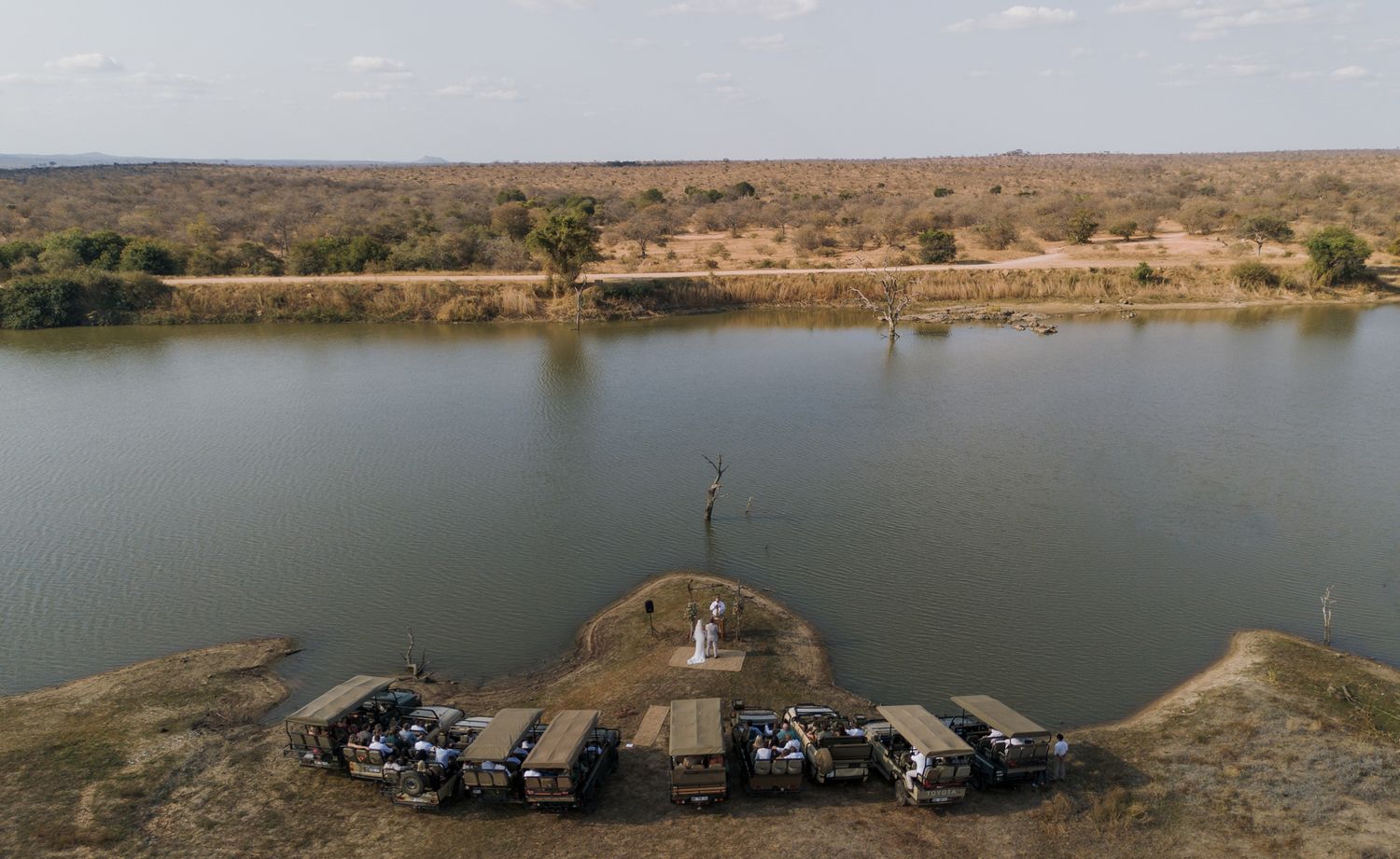 Panoramic aerial view of a lakeside venue surrounded by arid landscape.