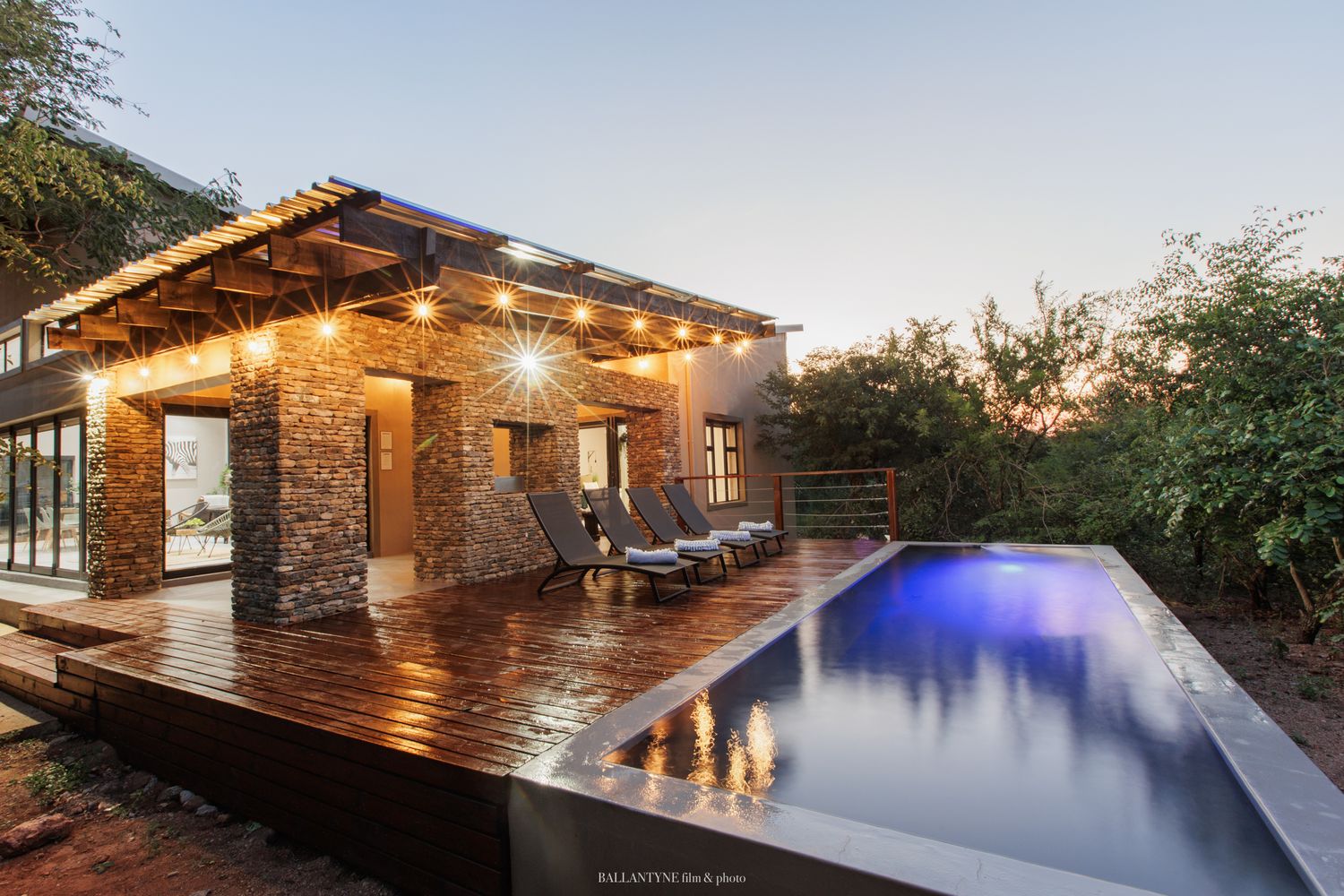Luxurious modern infinity pool with LED lighting overlooks scenic mountain views at twilight.