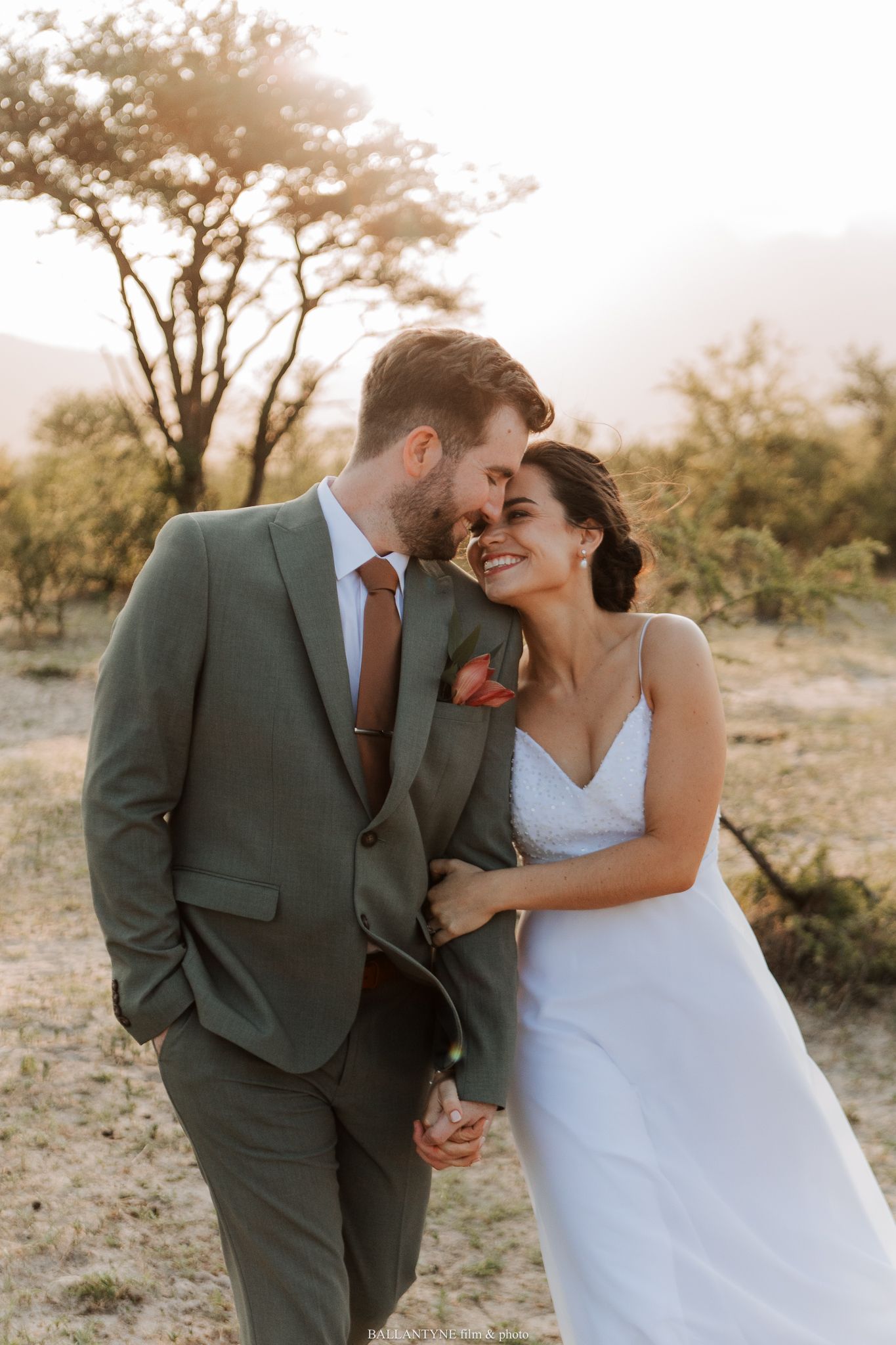 A romantic sunset portrait of newlyweds sharing an intimate moment in natural surroundings.