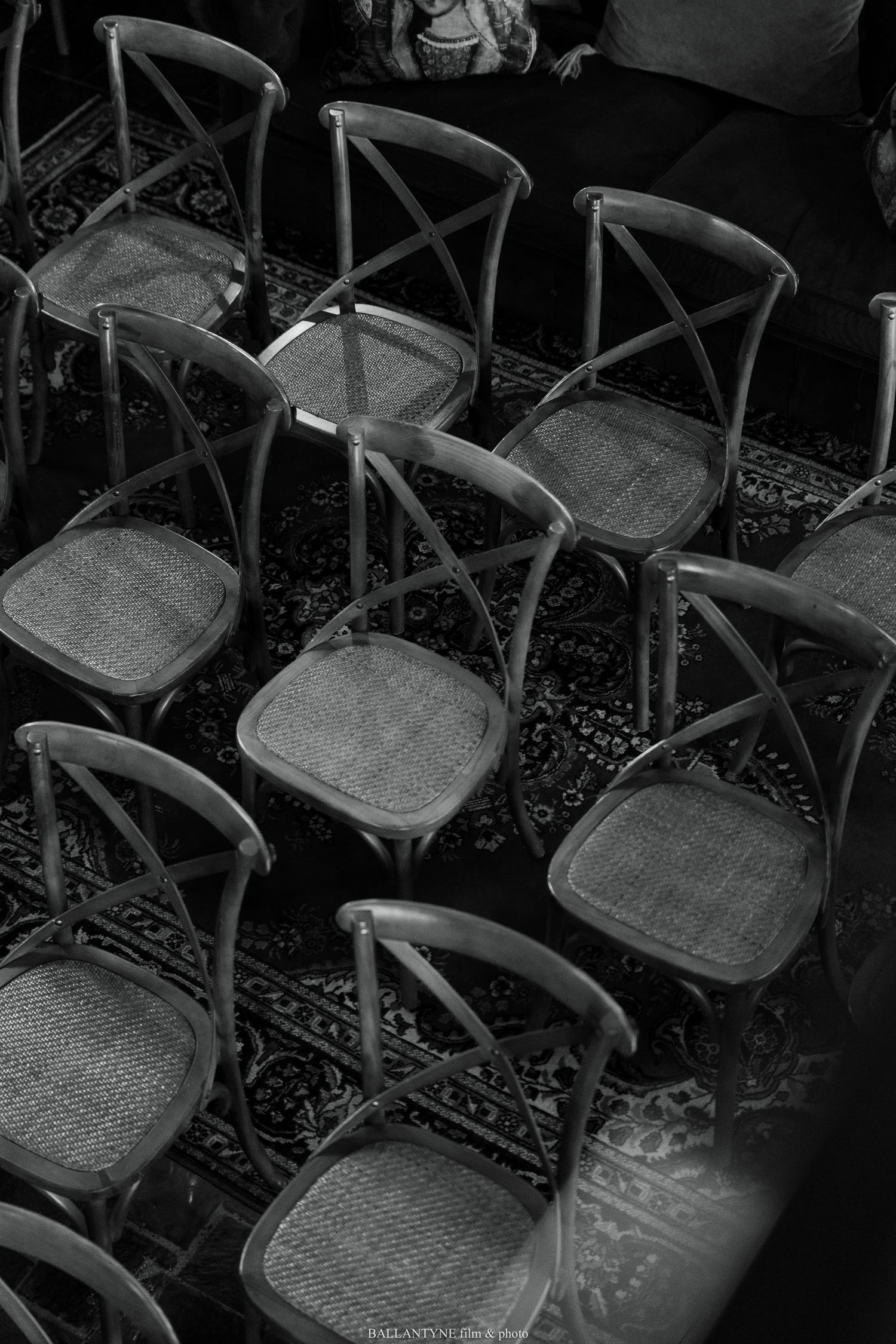 Rows of empty vintage crossback chairs arranged for wedding ceremony.