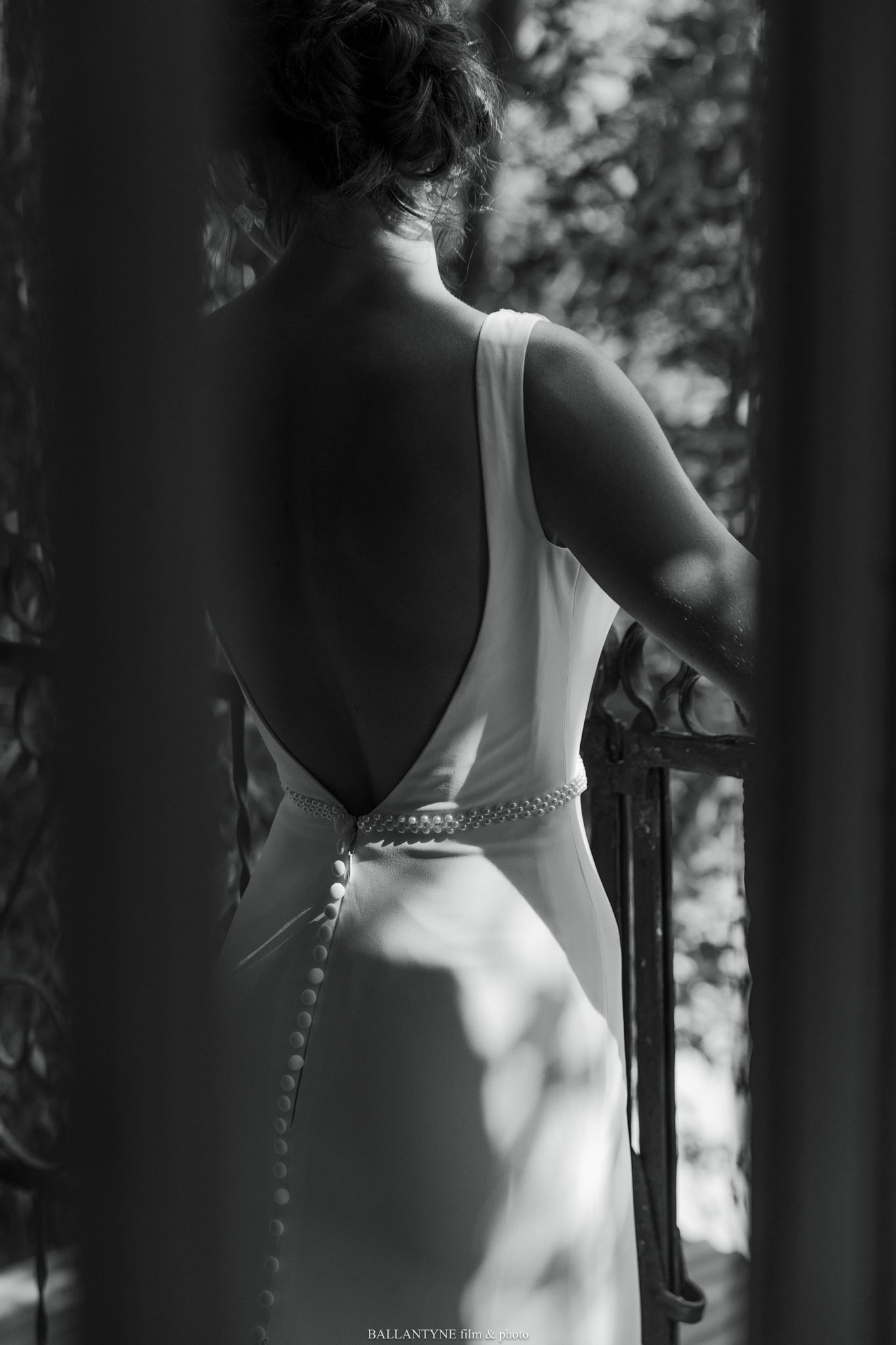 Artistic black and white photo showing the back details of an elegant wedding dress.