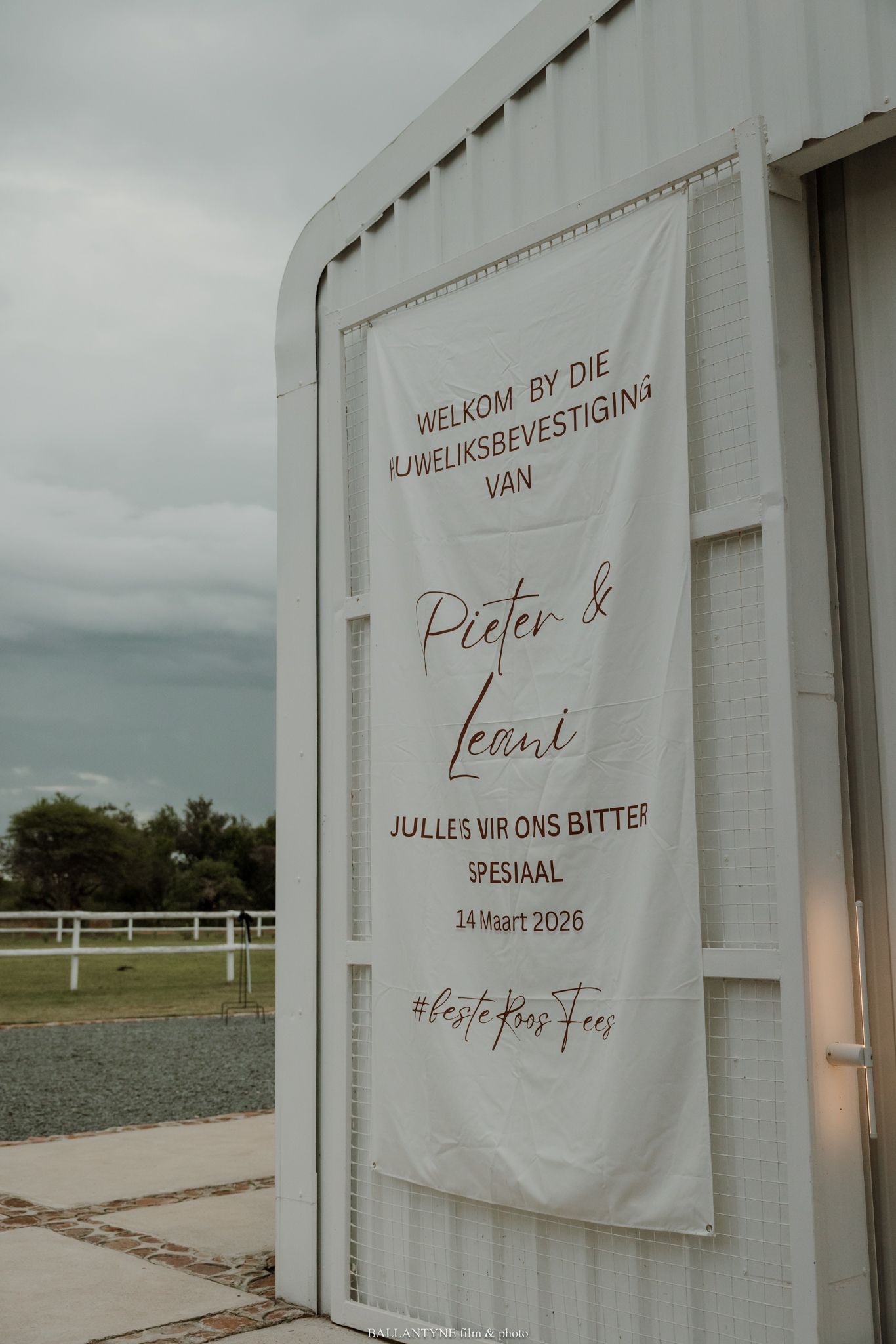 White wedding welcome banner for Pieter and Leani hanging on a barn wall, dated 14 Maart 2026, with Afrikaans text.