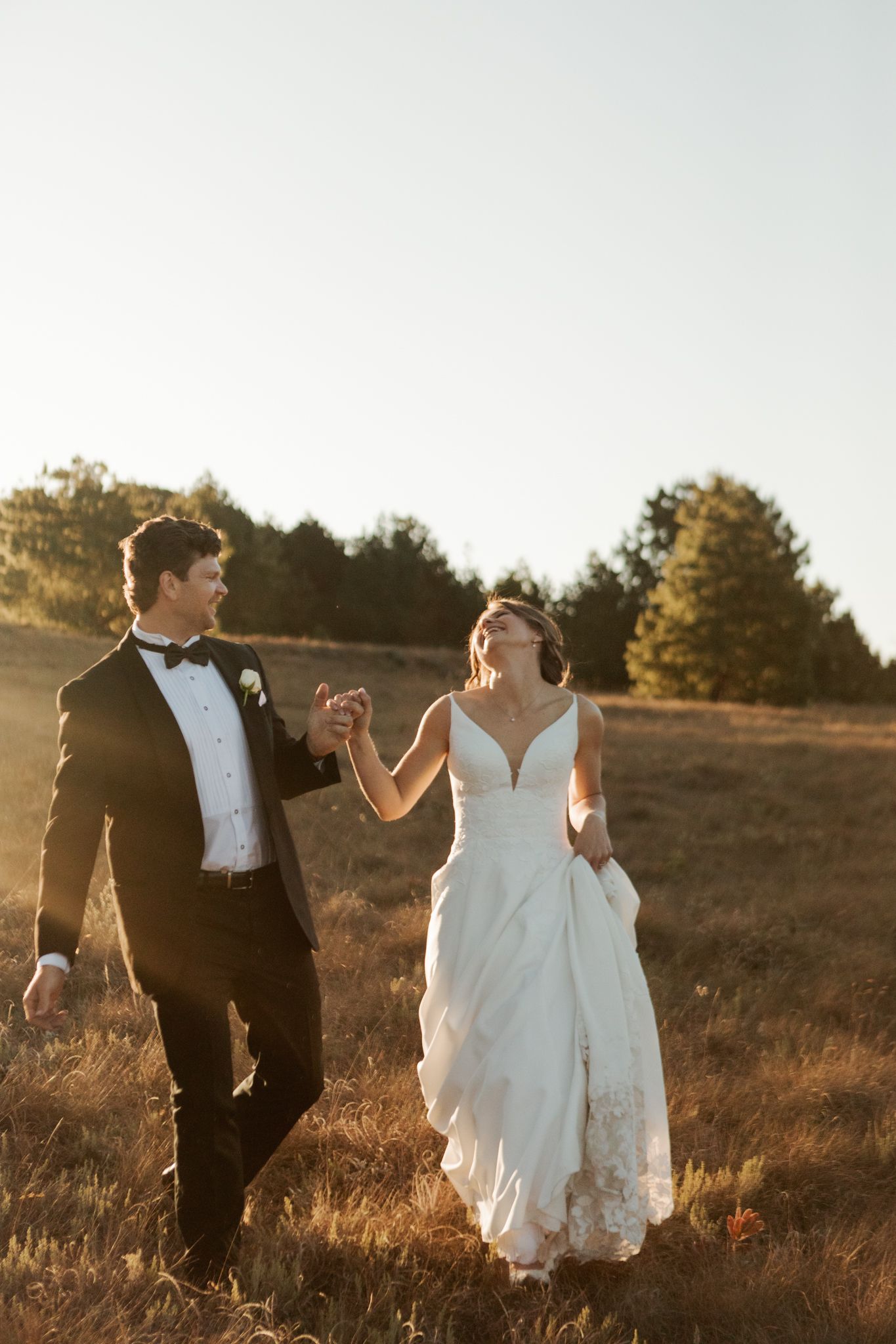 Couple dancing and twirling in a golden field during sunset.