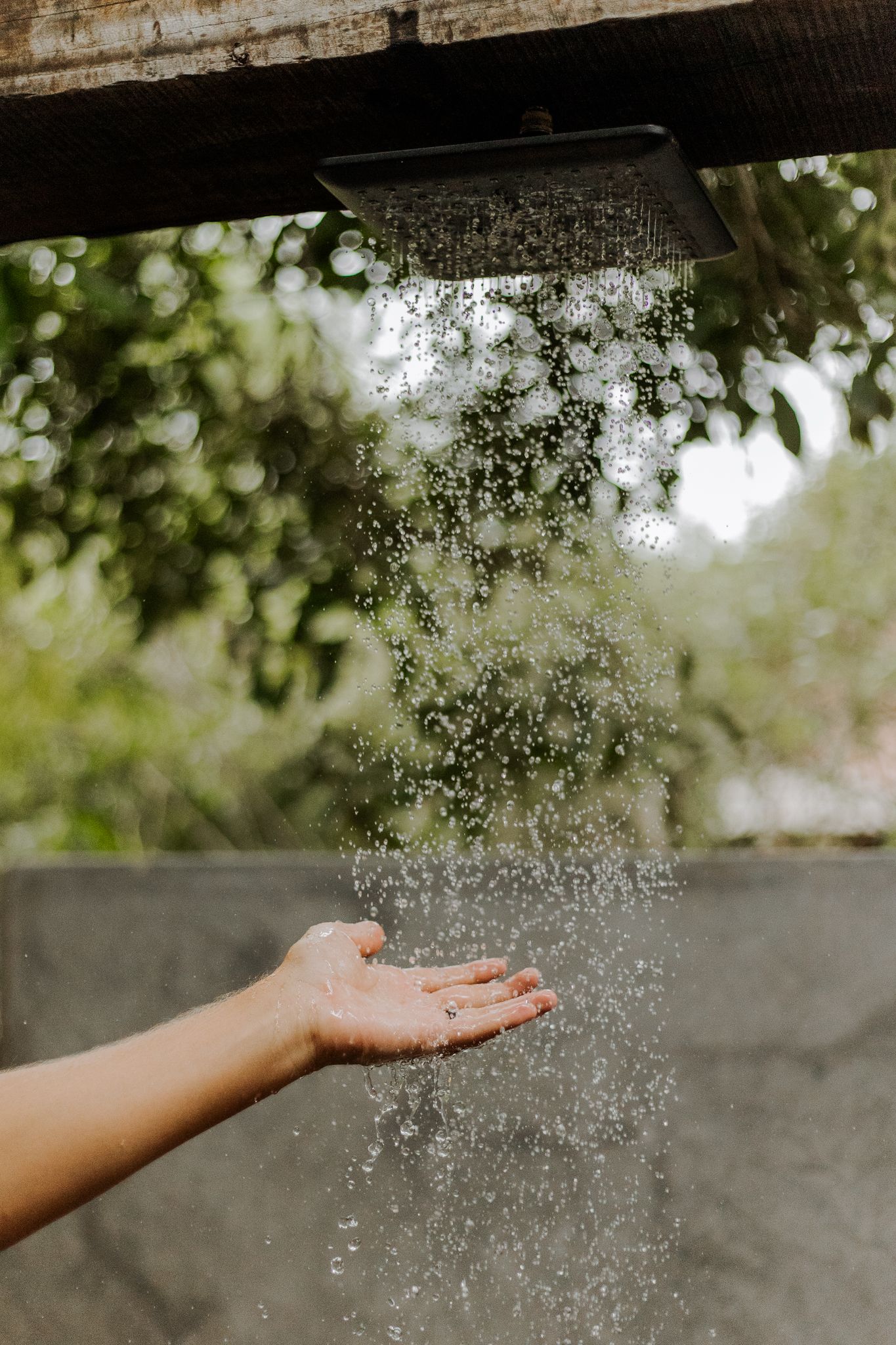 Hand catching falling water droplets in natural sunlight.