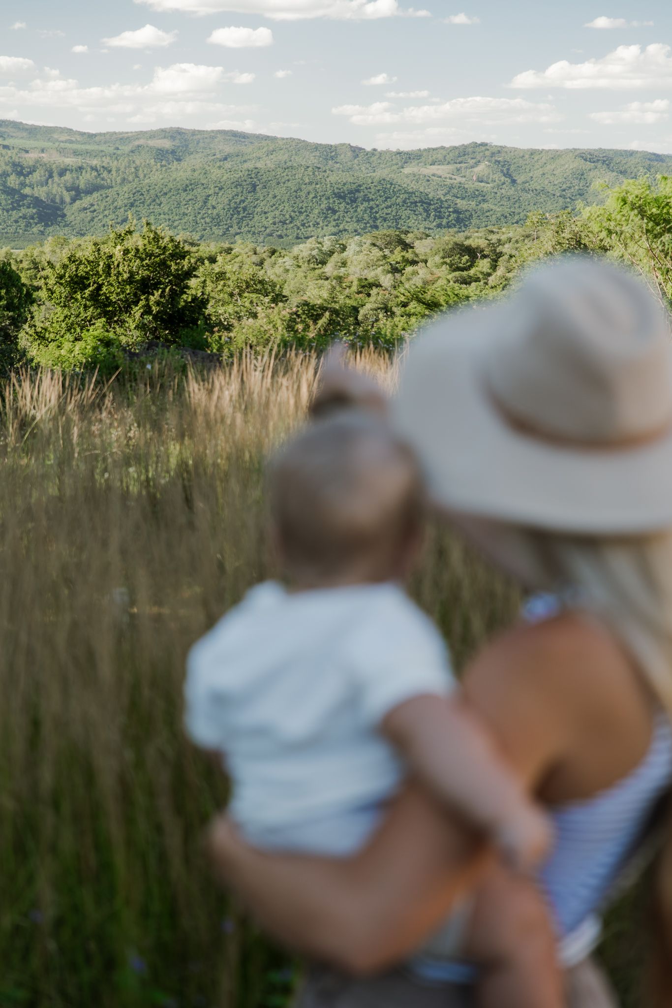 Two people in sun hats enjoy a scenic mountain view on a sunny summer day in the countryside.
