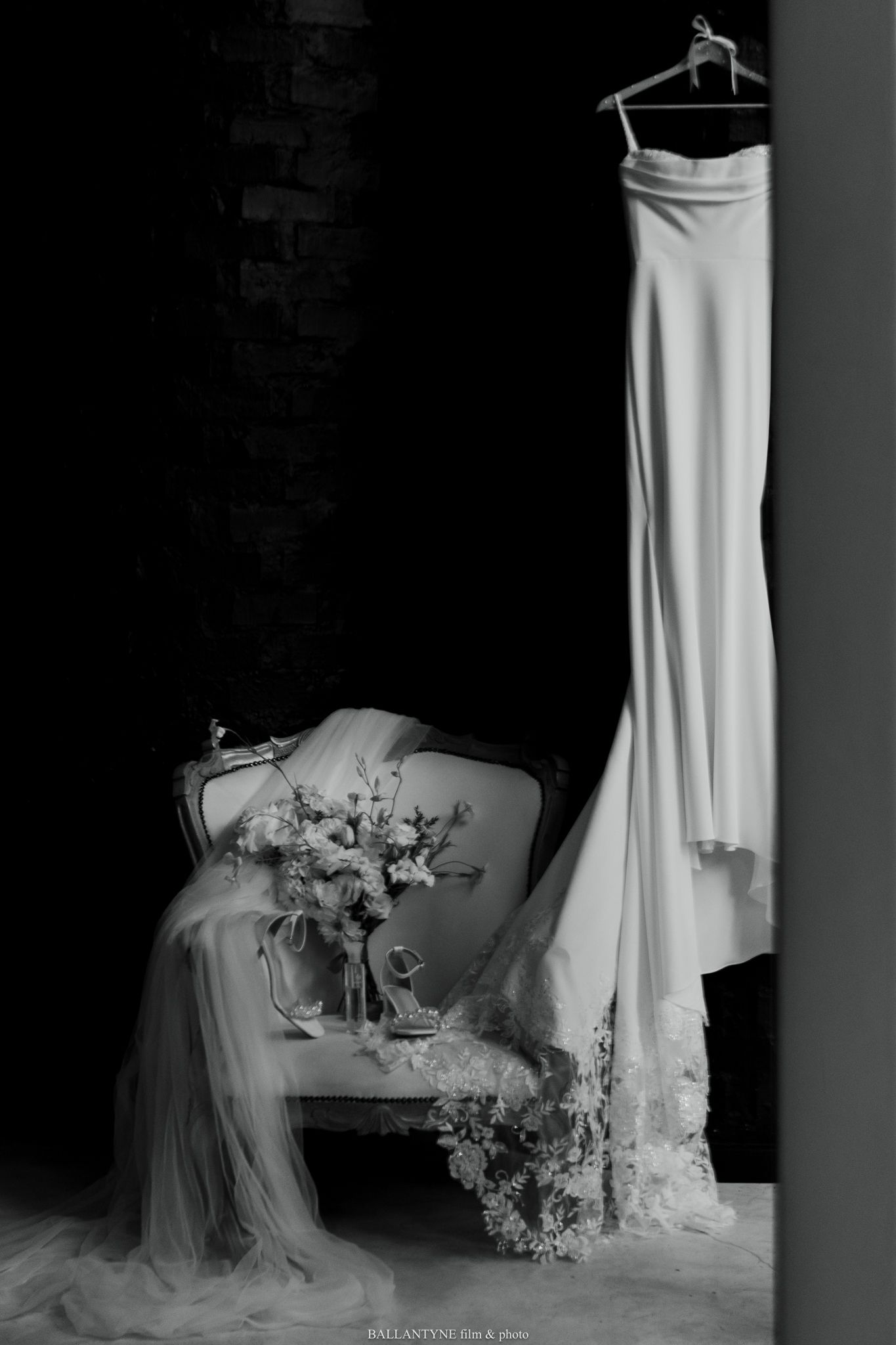 Minimalist wedding dress display with delicate floral arrangement on vintage furniture.