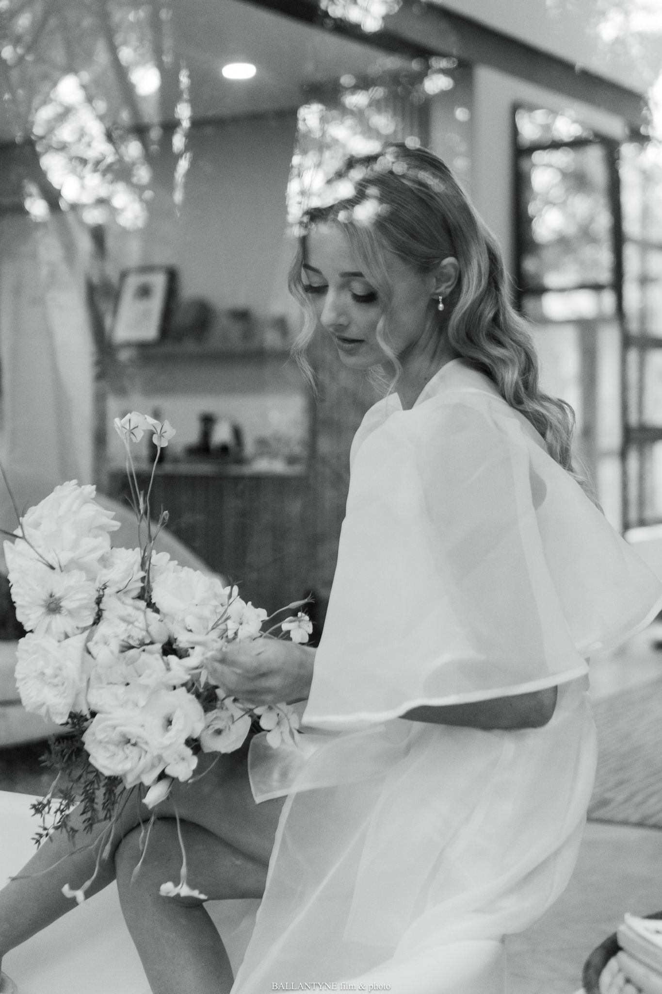 Black and white photo of bride holding bouquet in flowing white dress.