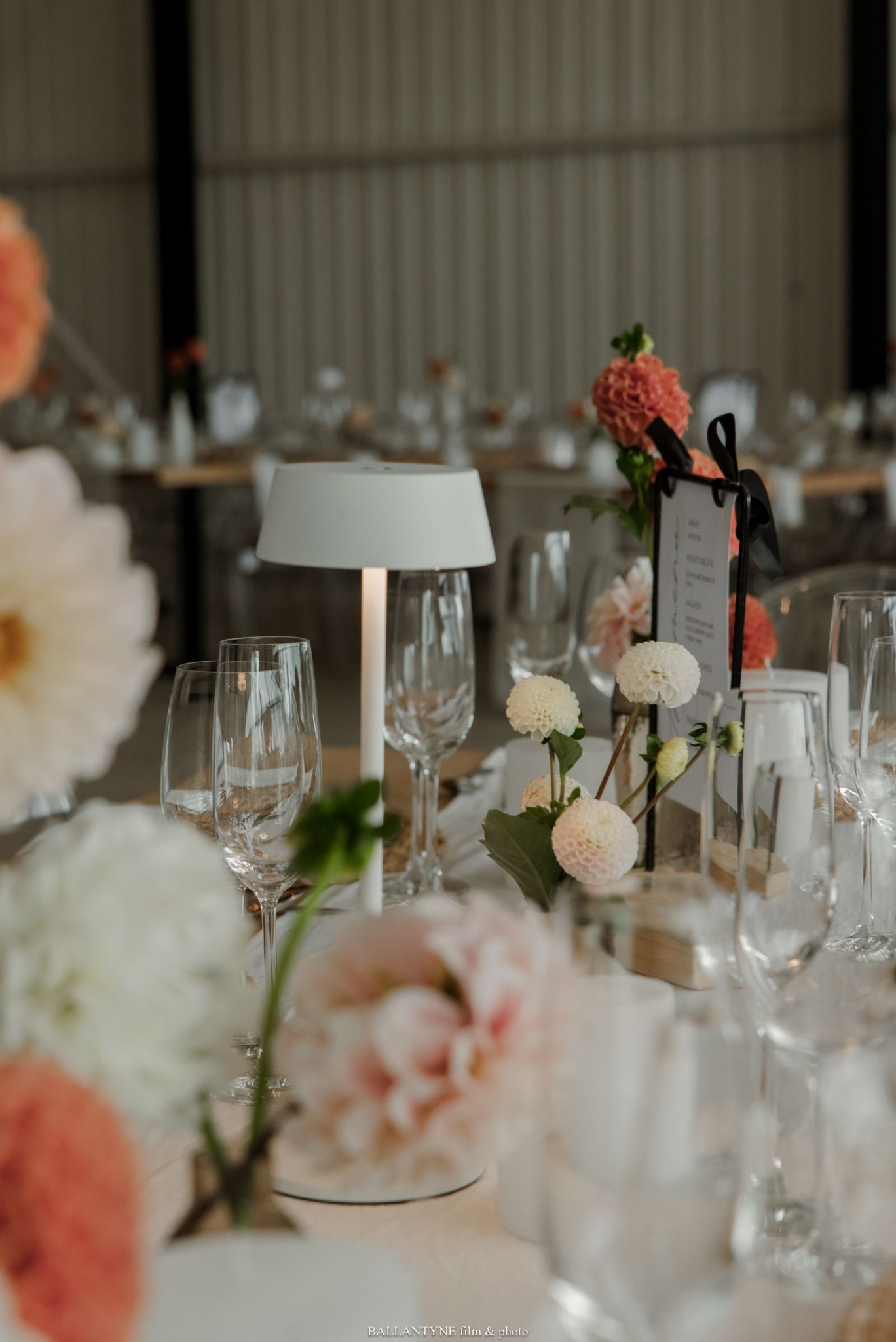 Elegant wedding reception table with blush florals, crystal glassware, and a modern white lamp centerpiece.