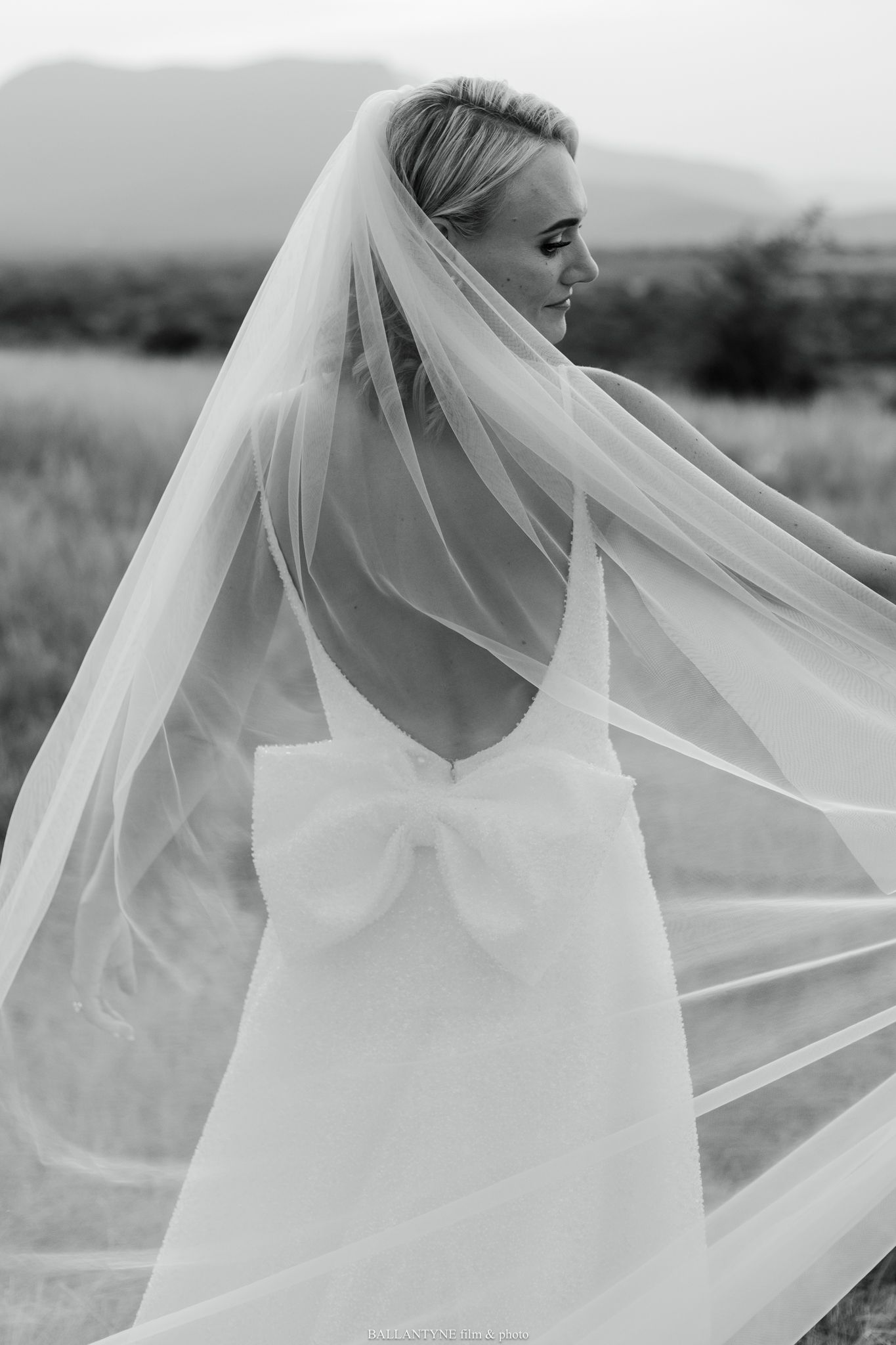 A dreamy black and white portrait of a bride with flowing veil in natural light.