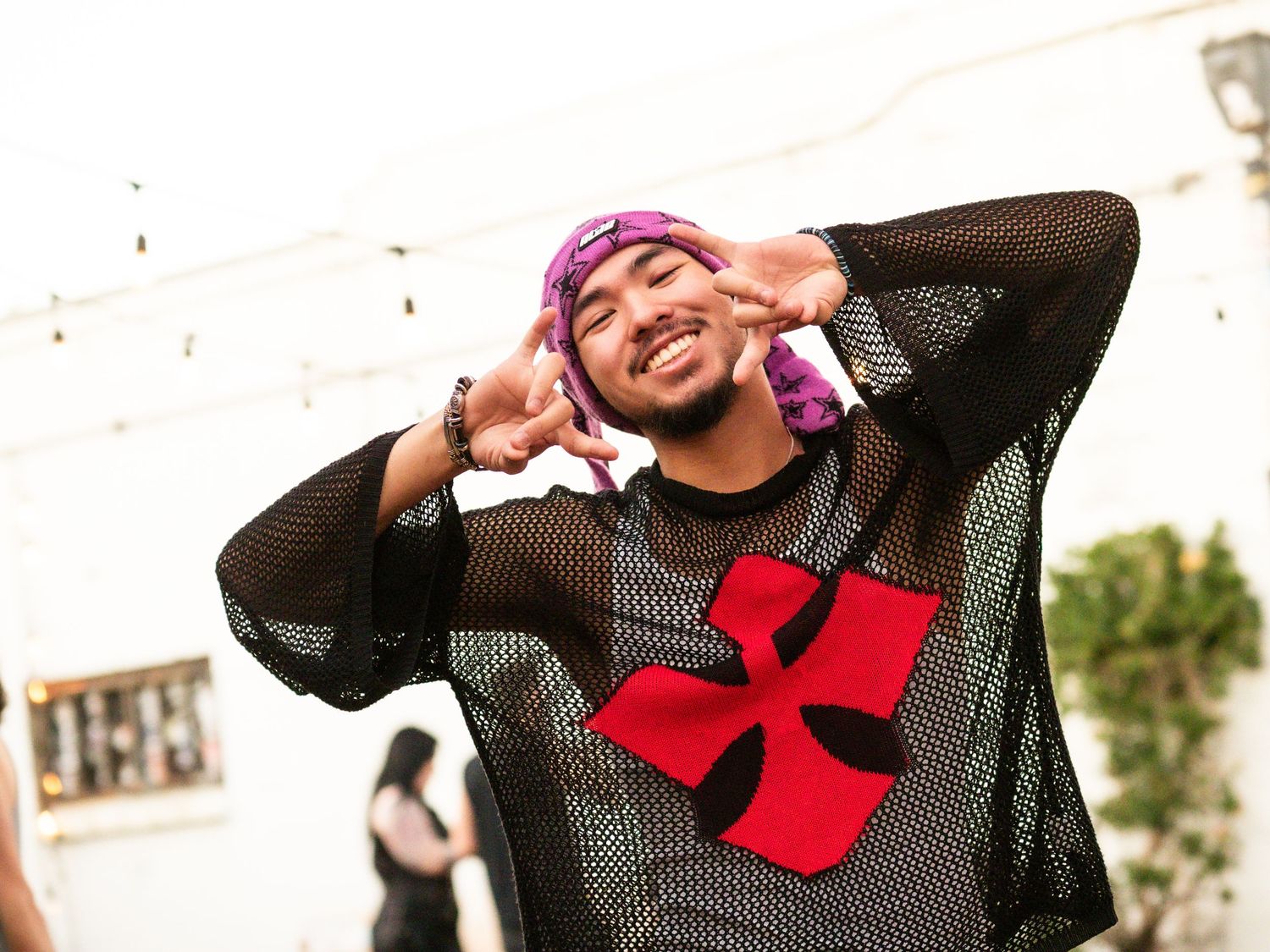 man smiling hand gesture pink hat black shirt
