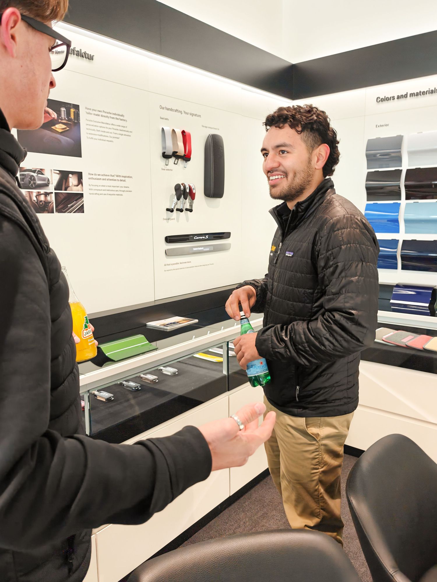 men in office facing eachother smiling holding water curly hair black jackets