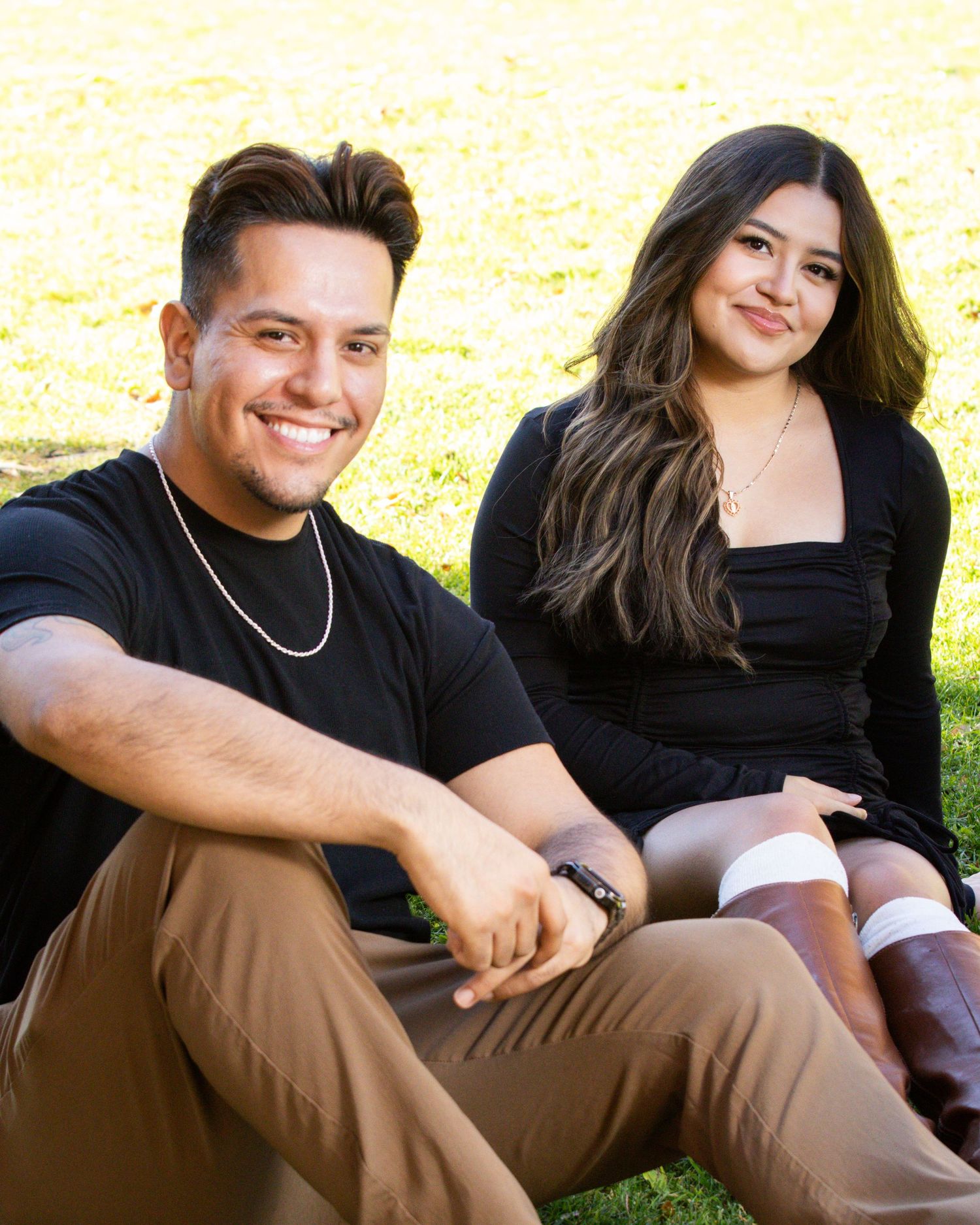 couple photo portrait sitting on grass smiling black shirts green background
