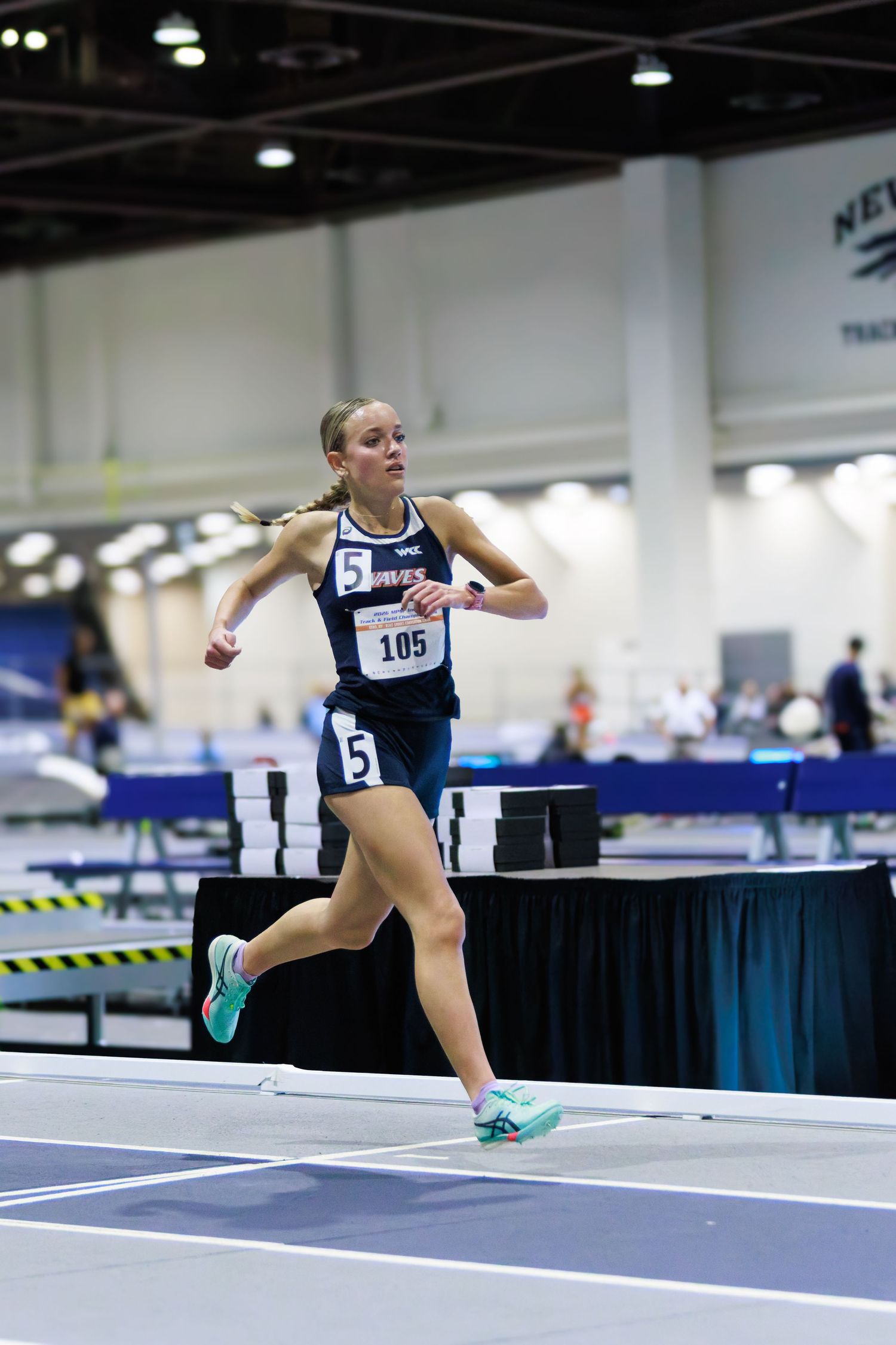 portrait woman running indoor track pinned number on outfit college athelete