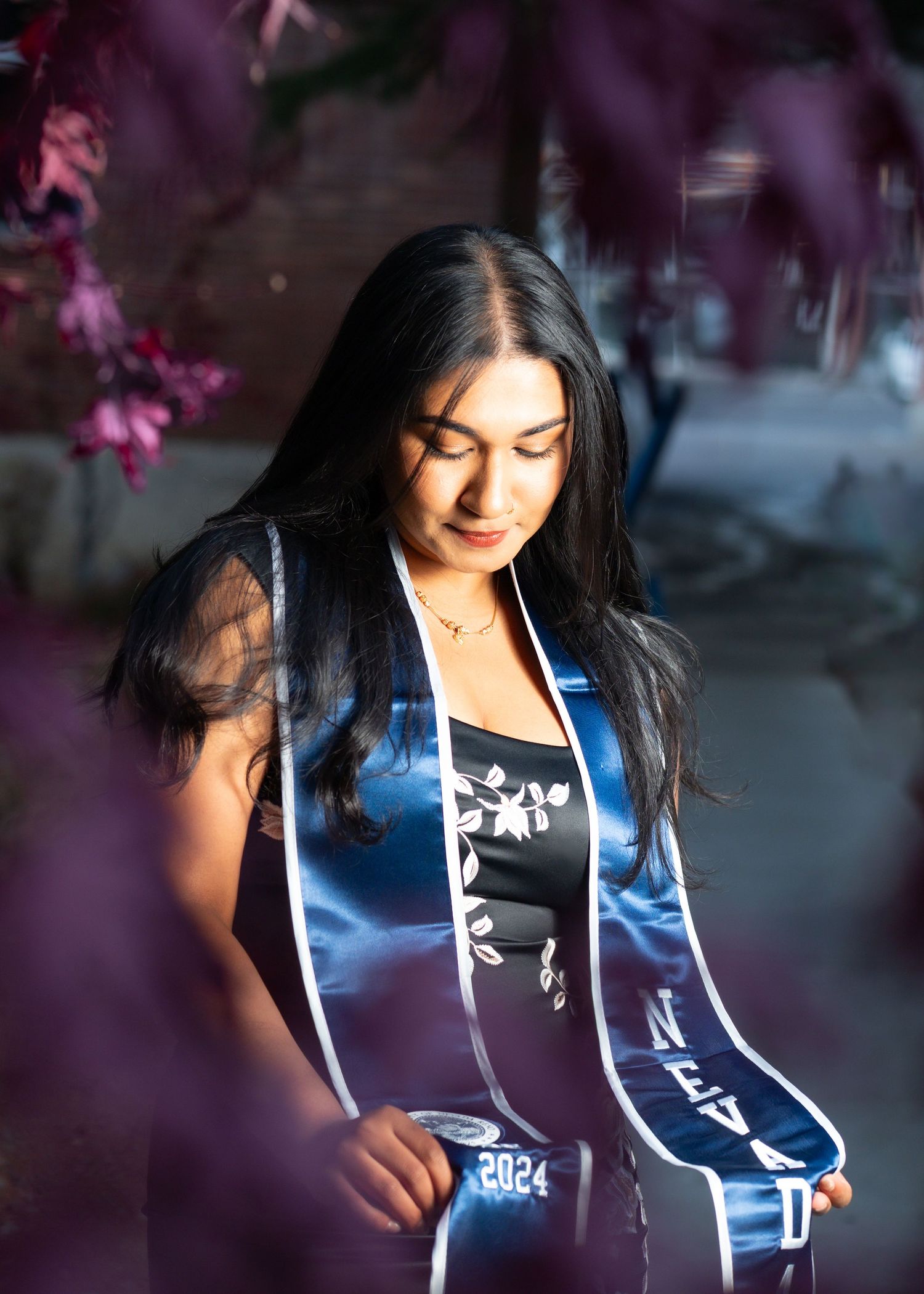 portrait graduate purple flowers black outfit woman looking down