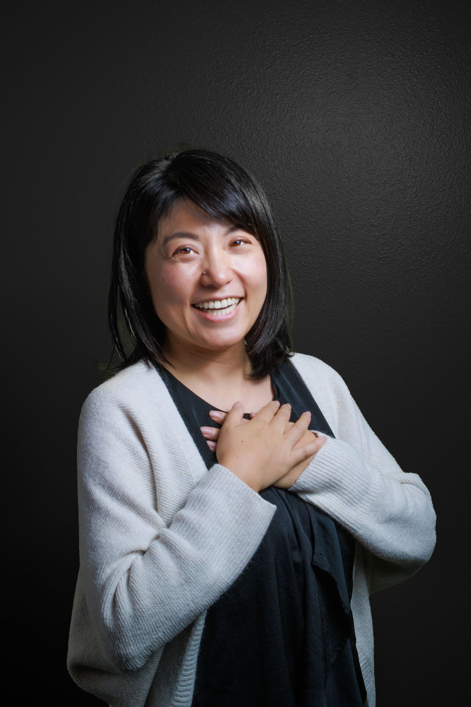 Portrait, woman smiling black background grey shirt