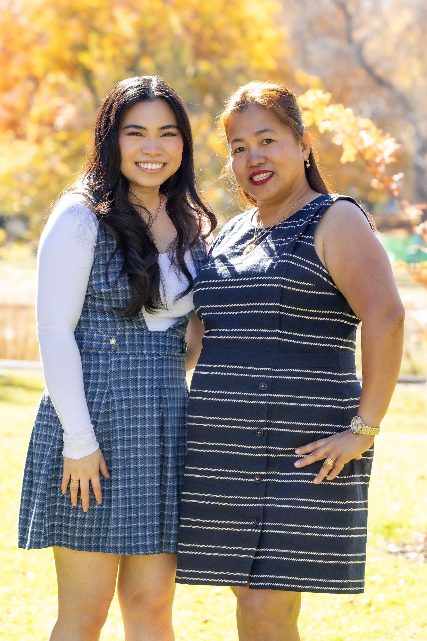group portrait arm around waist blue outfits smiling 2 women green background