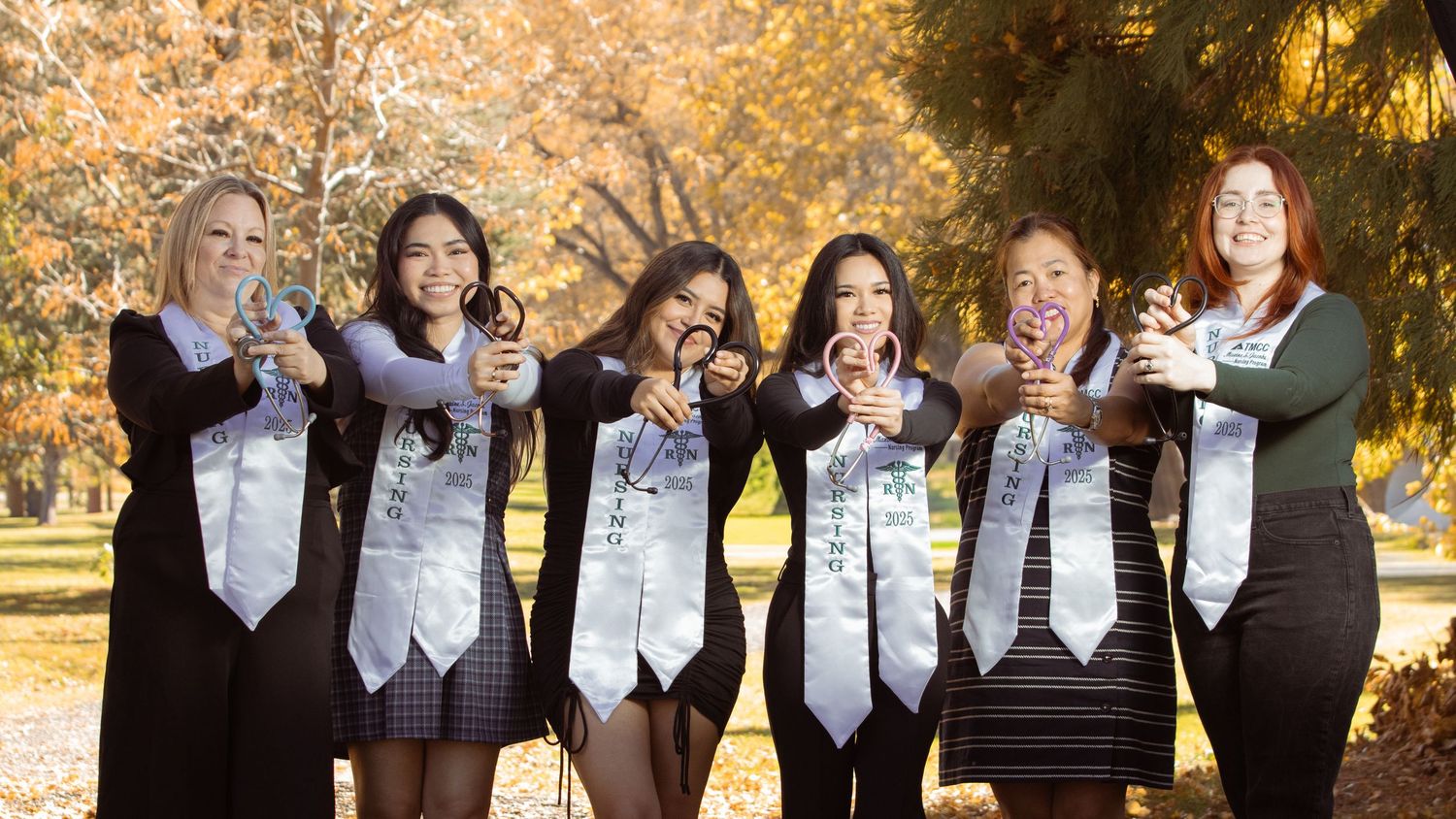 group graduates landscape nurses holding stethoscopes in shape of heart group women