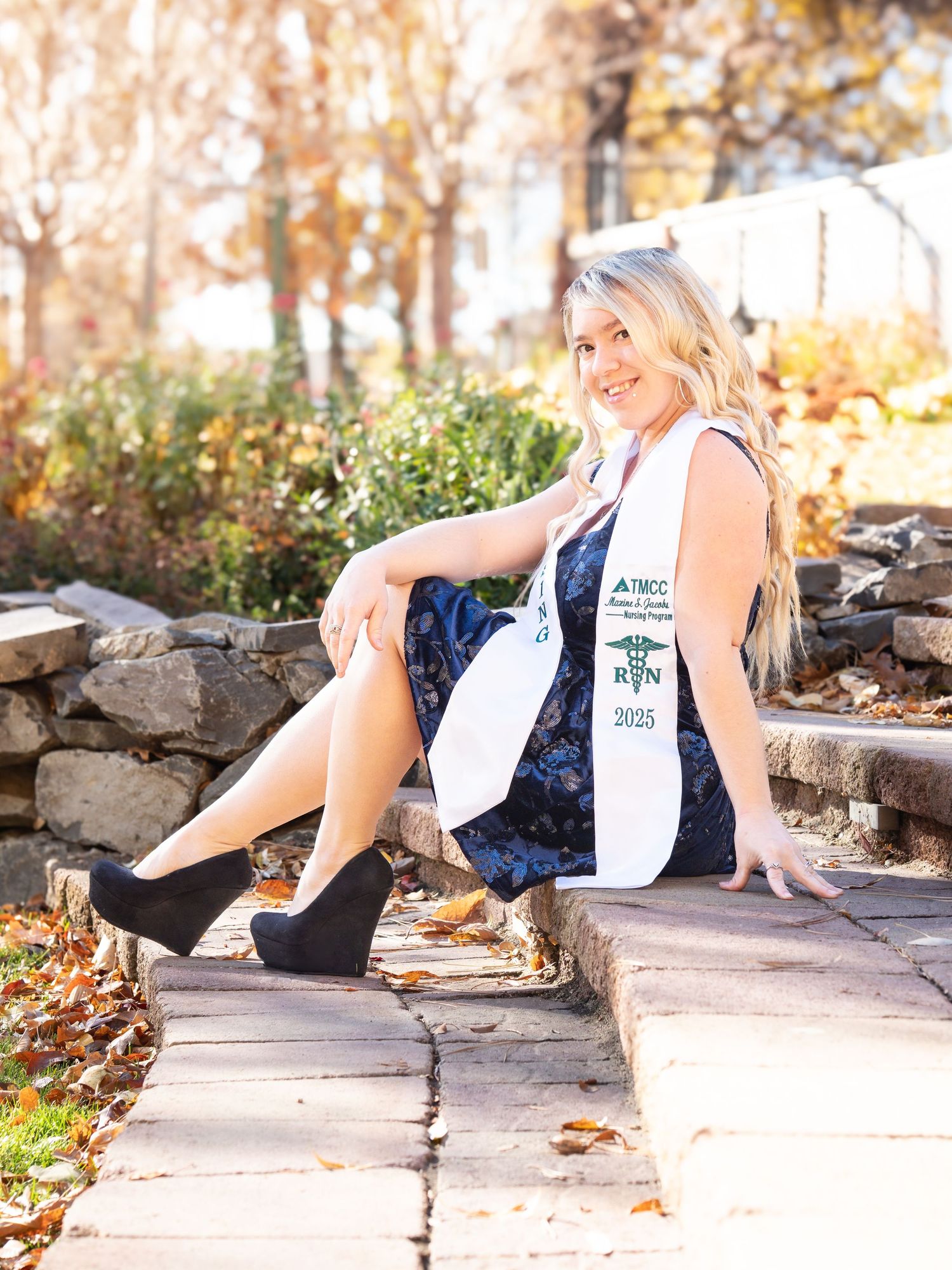 Portrait graduation photo, woman blue dress bright nature area posed