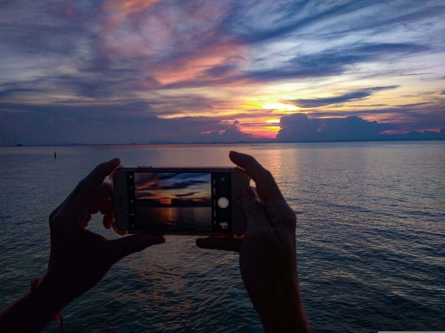 holding phone to sunset, screen showing landscape