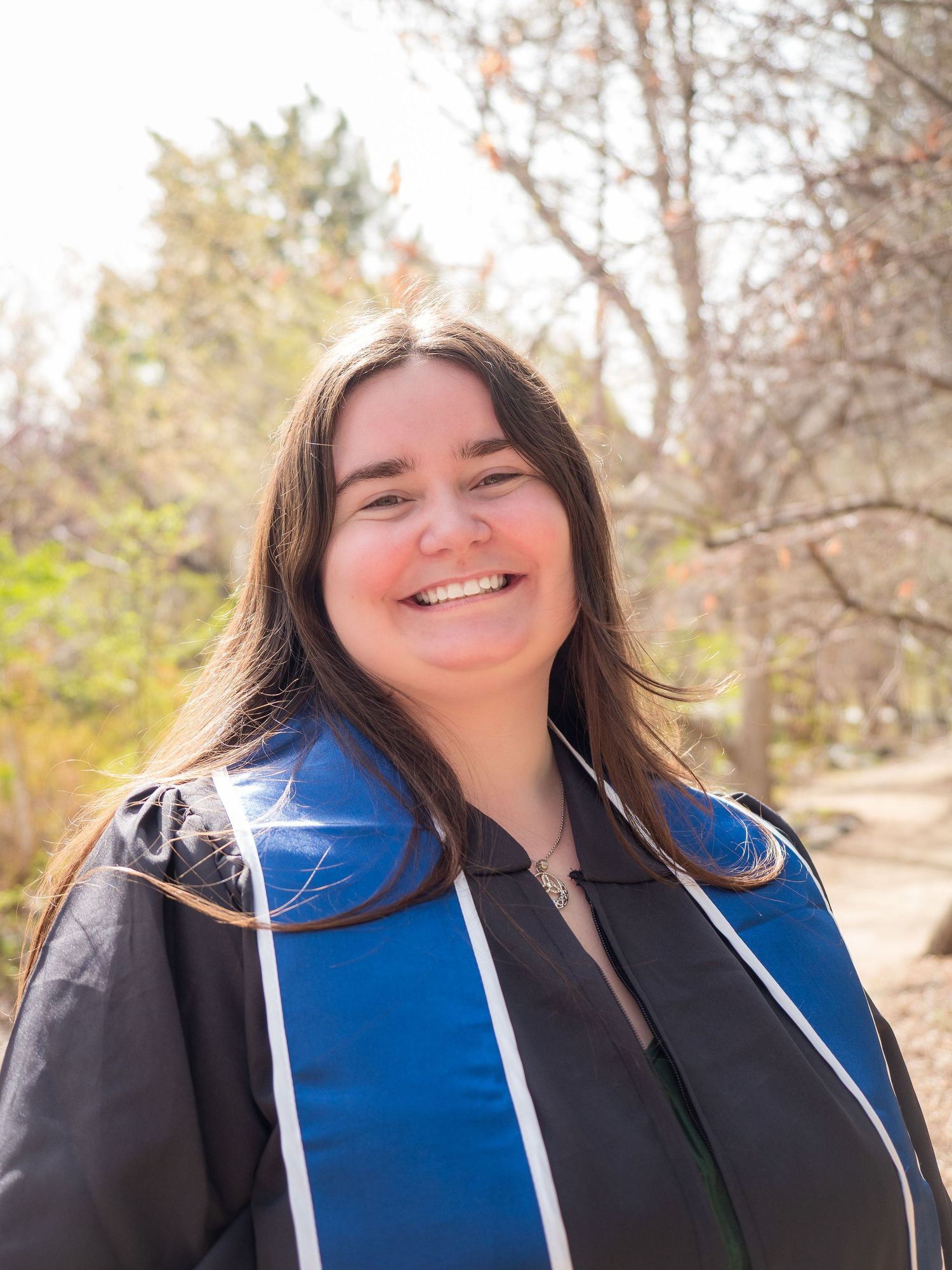 woman grad portrait gown UNR green background smiling