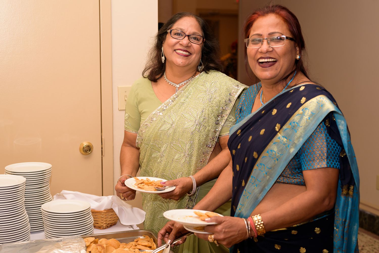 Wedding guests in traditional Indian saris enjoy a meal at the reception.