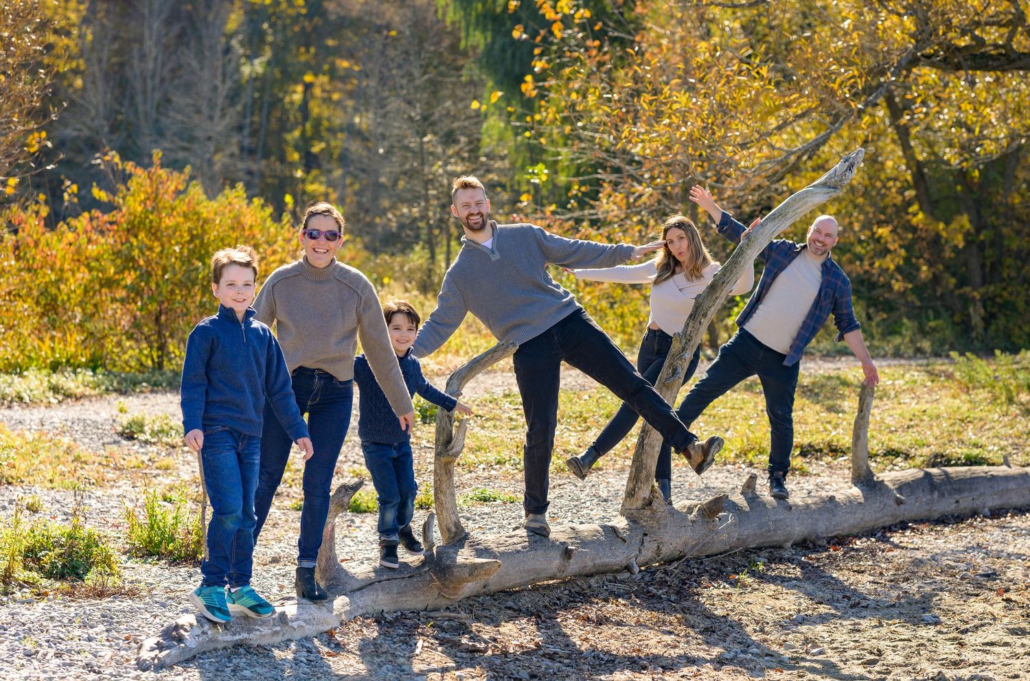 A group of people standing together on a rocky path during a sunny autumn day with golden foliage.