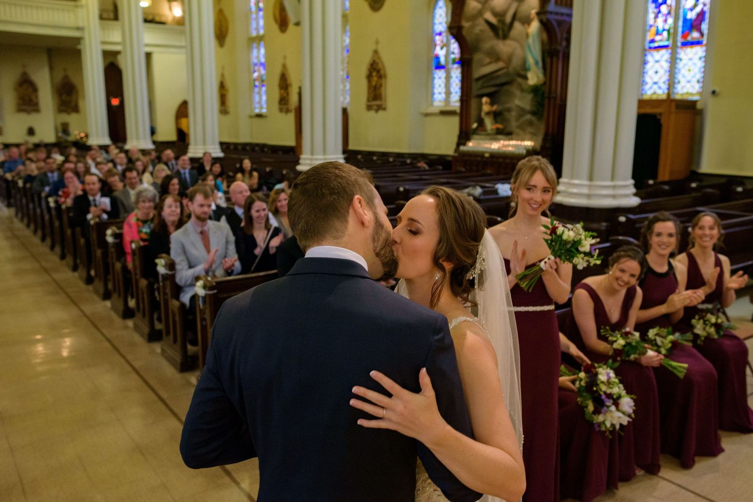 Wedding ceremony photos inside ornate church with stained glass windows and traditional architecture.