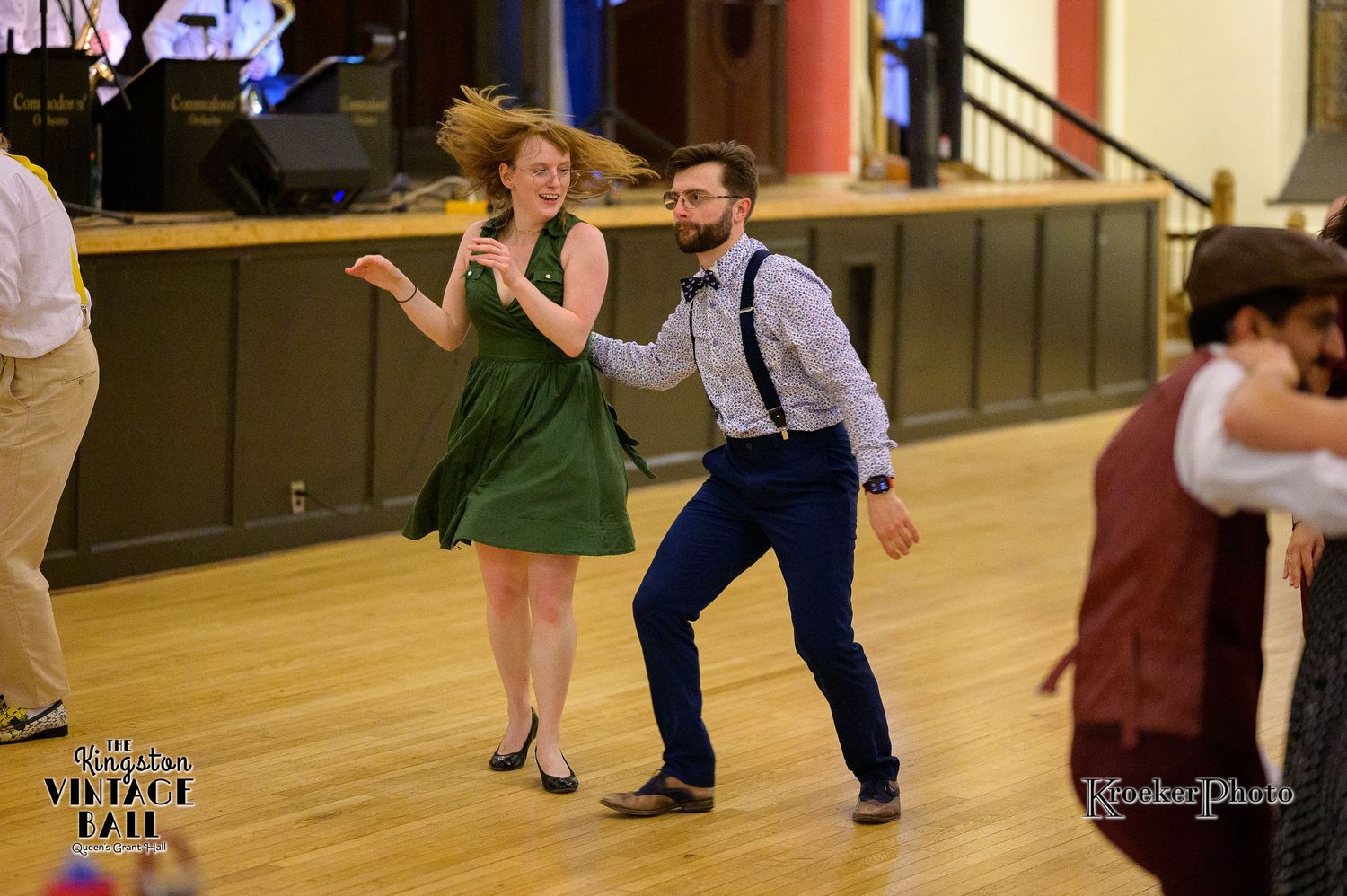 Wedding guests perform choreographed dance moves on a wooden dance floor.