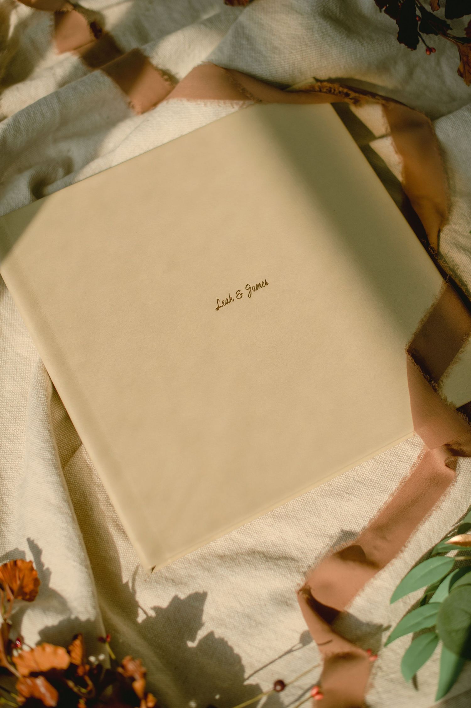 A white album with soft lighting and decorative foliage accents.