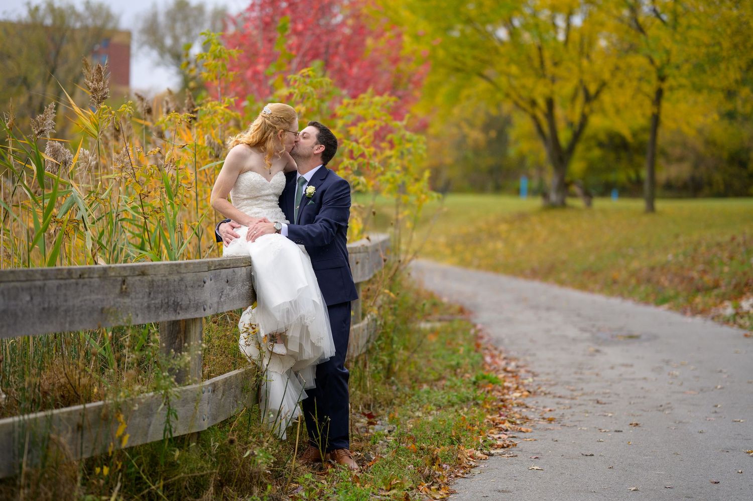 Autumn wedding photos on path with vibrant red and yellow fall foliage.