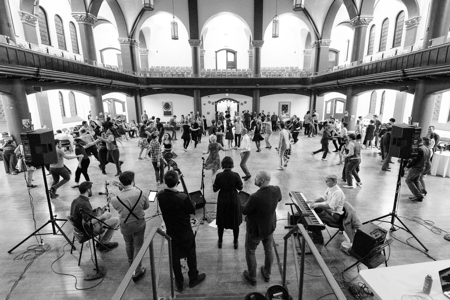 Wide-angle shot of a historic ballroom with dancers scattered throughout the space.