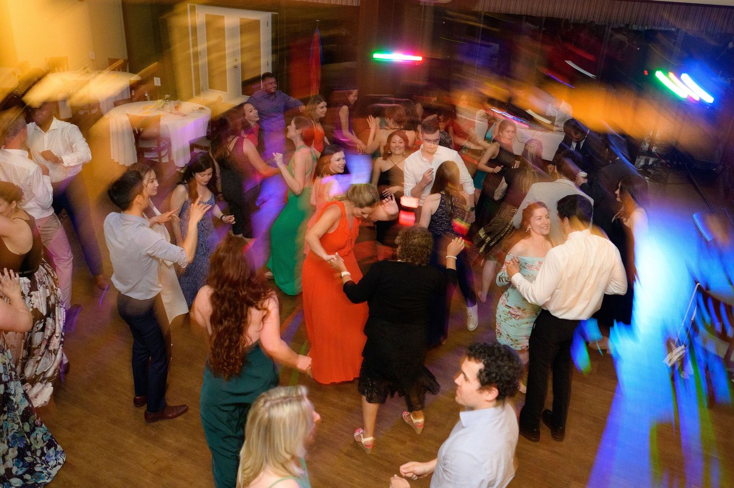 Dance party with colourful lighting and people dancing in a reception hall.